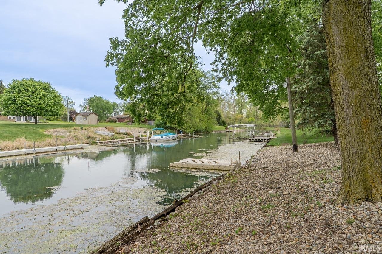 Waterfront property featuring a canal with multiple boat slips, a floating dock, and mature trees providing natural screening