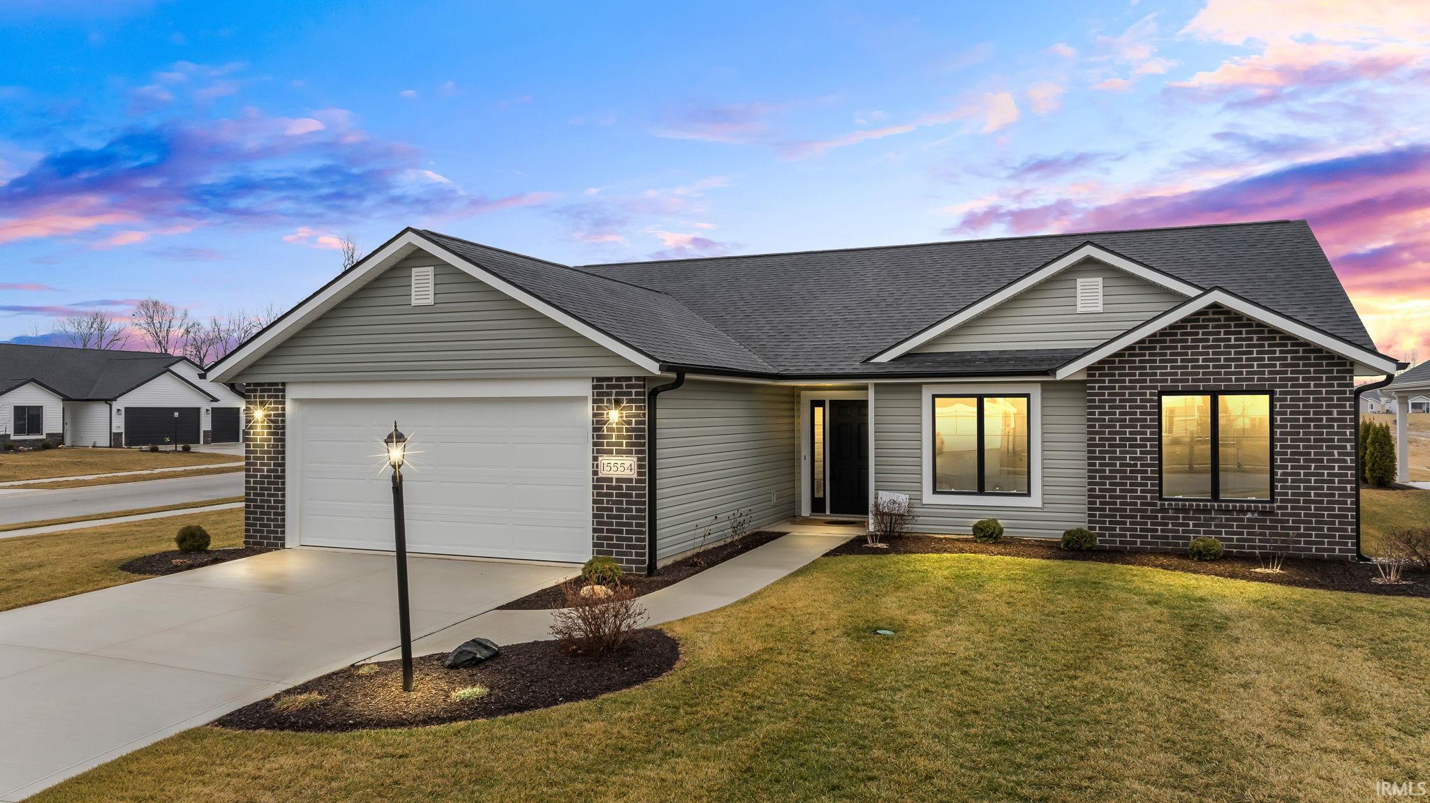 Modern ranch-style home featuring a two-car garage, concrete driveway, and a combination of horizontal siding and dark brick veneer