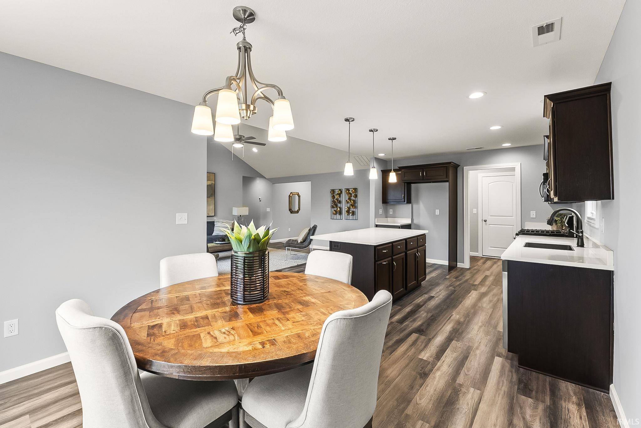 Open-concept kitchen and dining area featuring wood-finish flooring, dark wood cabinetry, white countertops, and recessed lighting