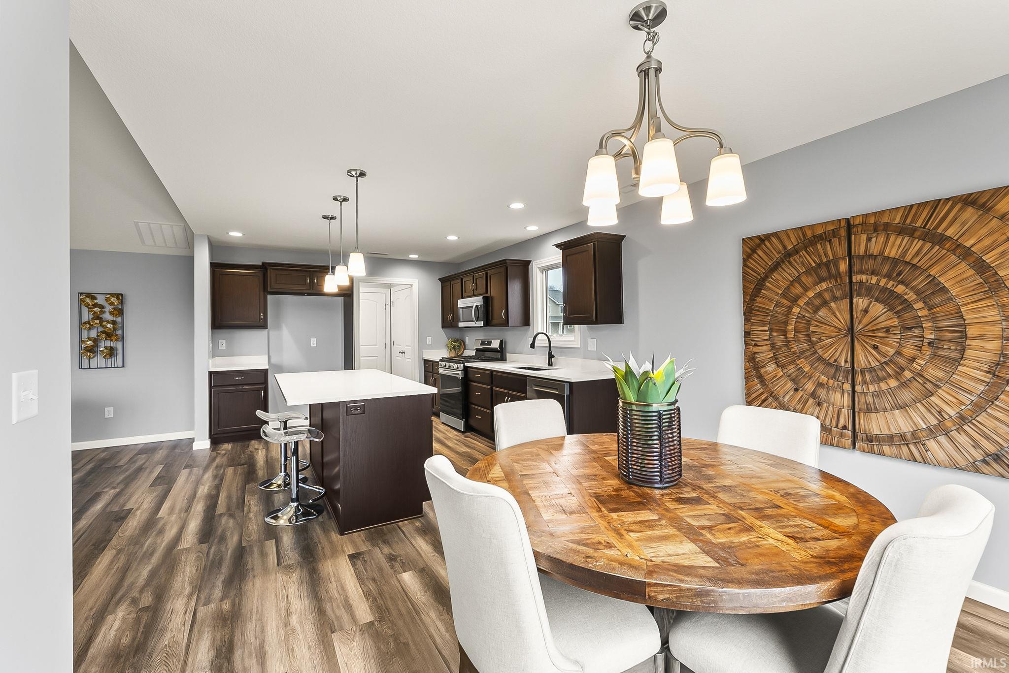 Spacious kitchen and dining area featuring wood-finish flooring, dark wood cabinetry, and white countertops