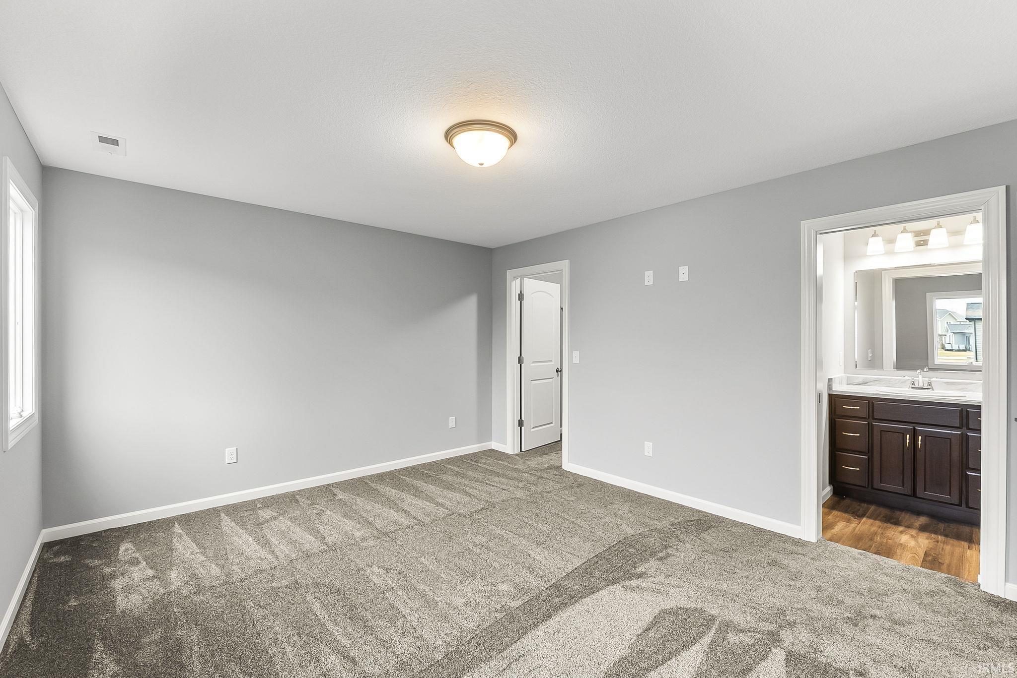 Spacious room featuring neutral carpeting, light gray wall paint, and a semi-flush mount ceiling light