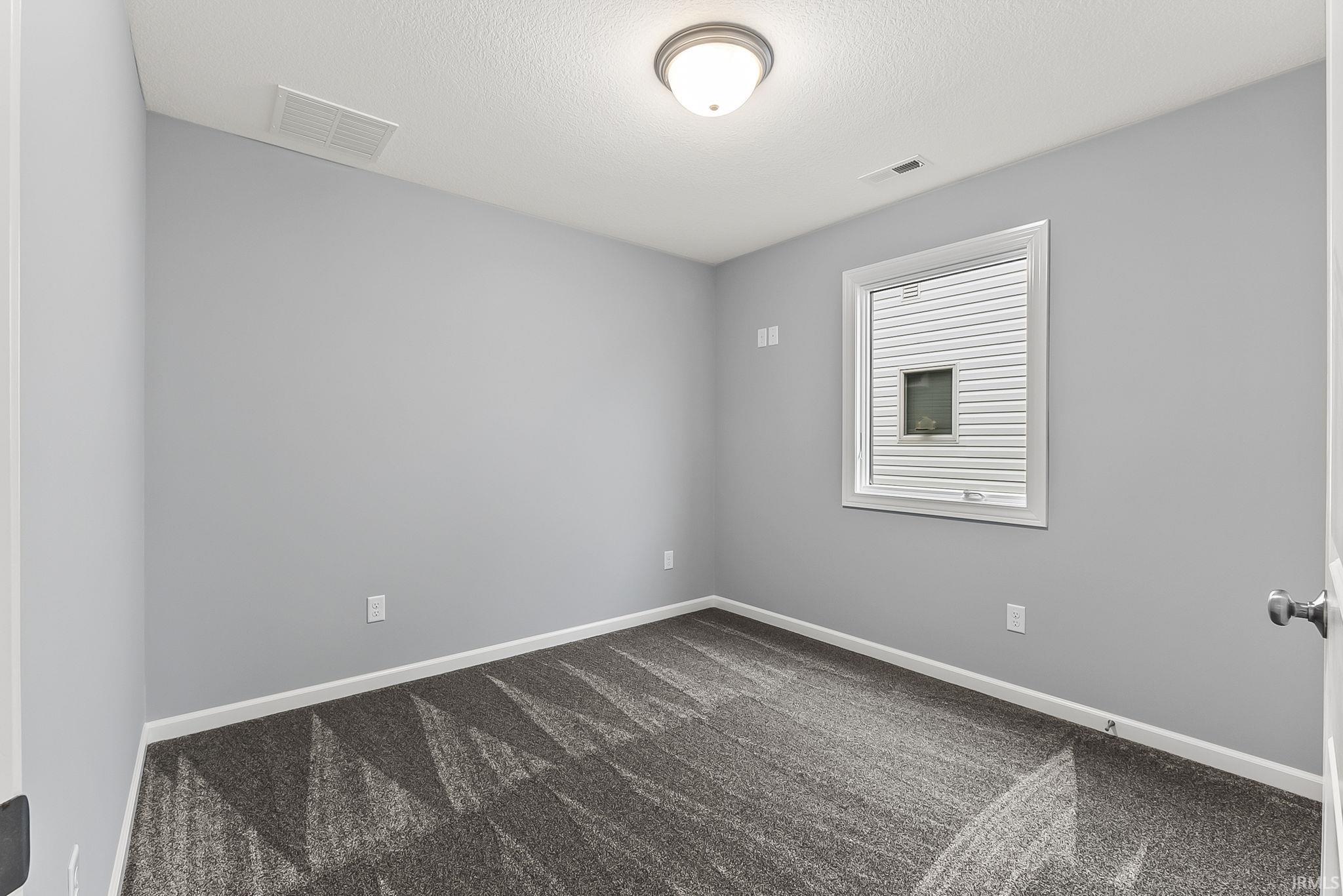 Room featuring light gray walls, white trim, and patterned carpeting