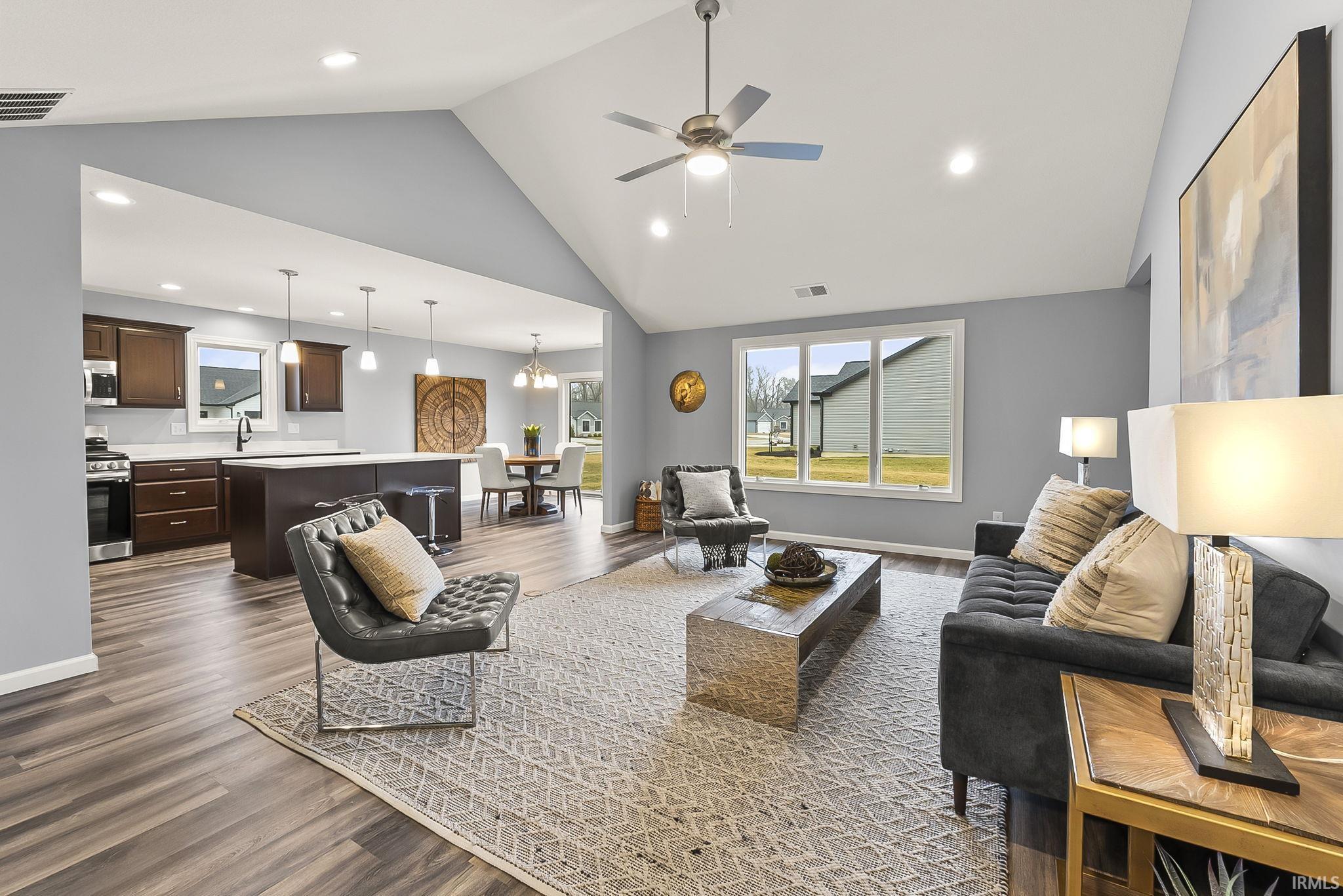Vaulted ceiling living room featuring wood-finish flooring, a ceiling fan with integrated lighting, and multiple recessed lights