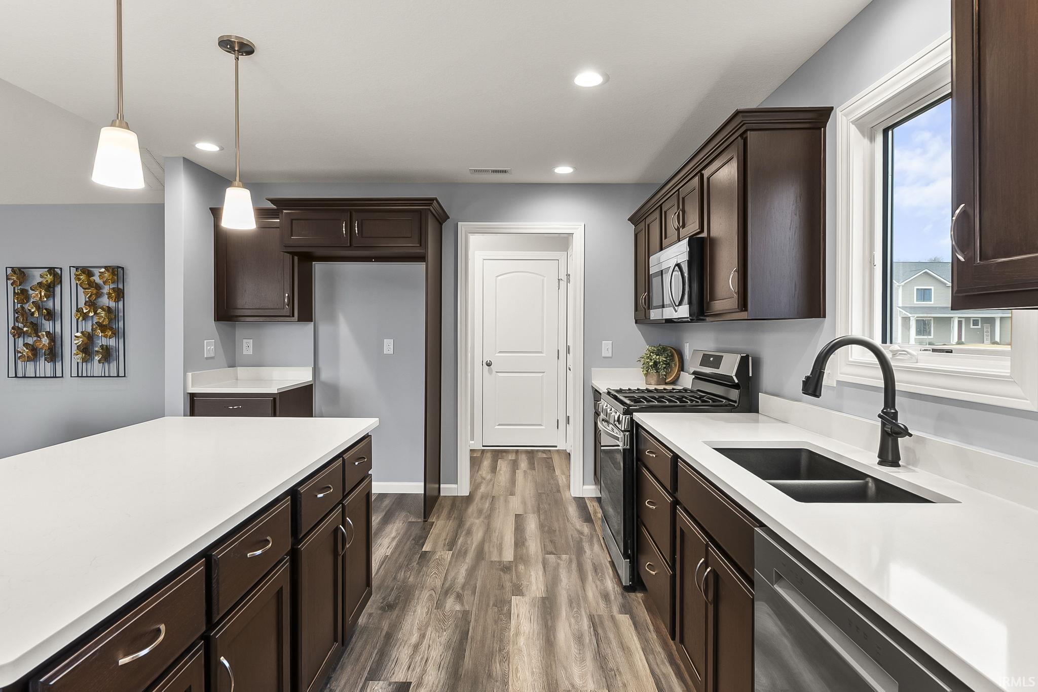 Kitchen with dark wood-finish cabinetry, white countertops, and wood-finish flooring