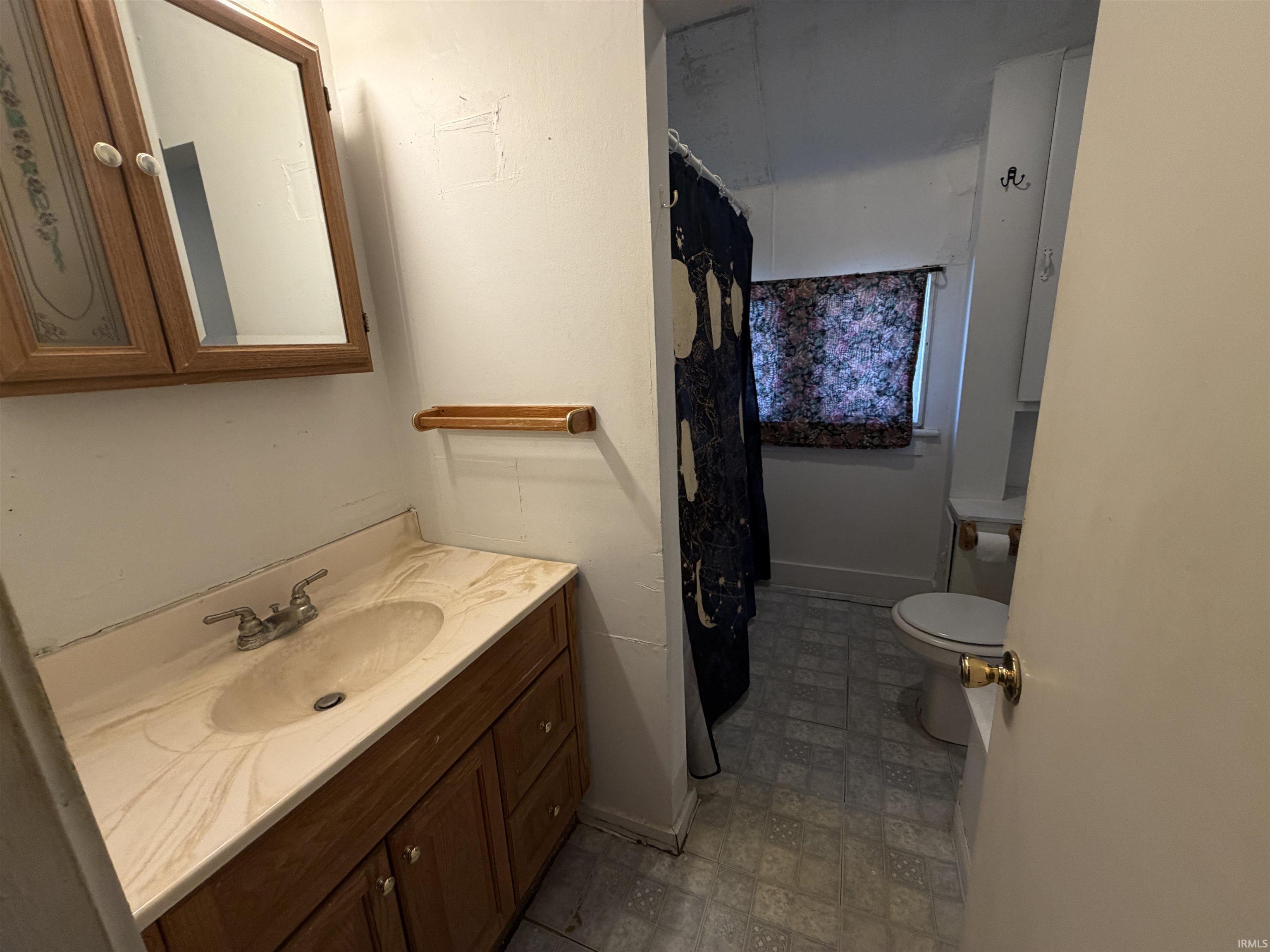 Bathroom featuring a wood-finish vanity with an integrated sink and a wood-frame medicine cabinet