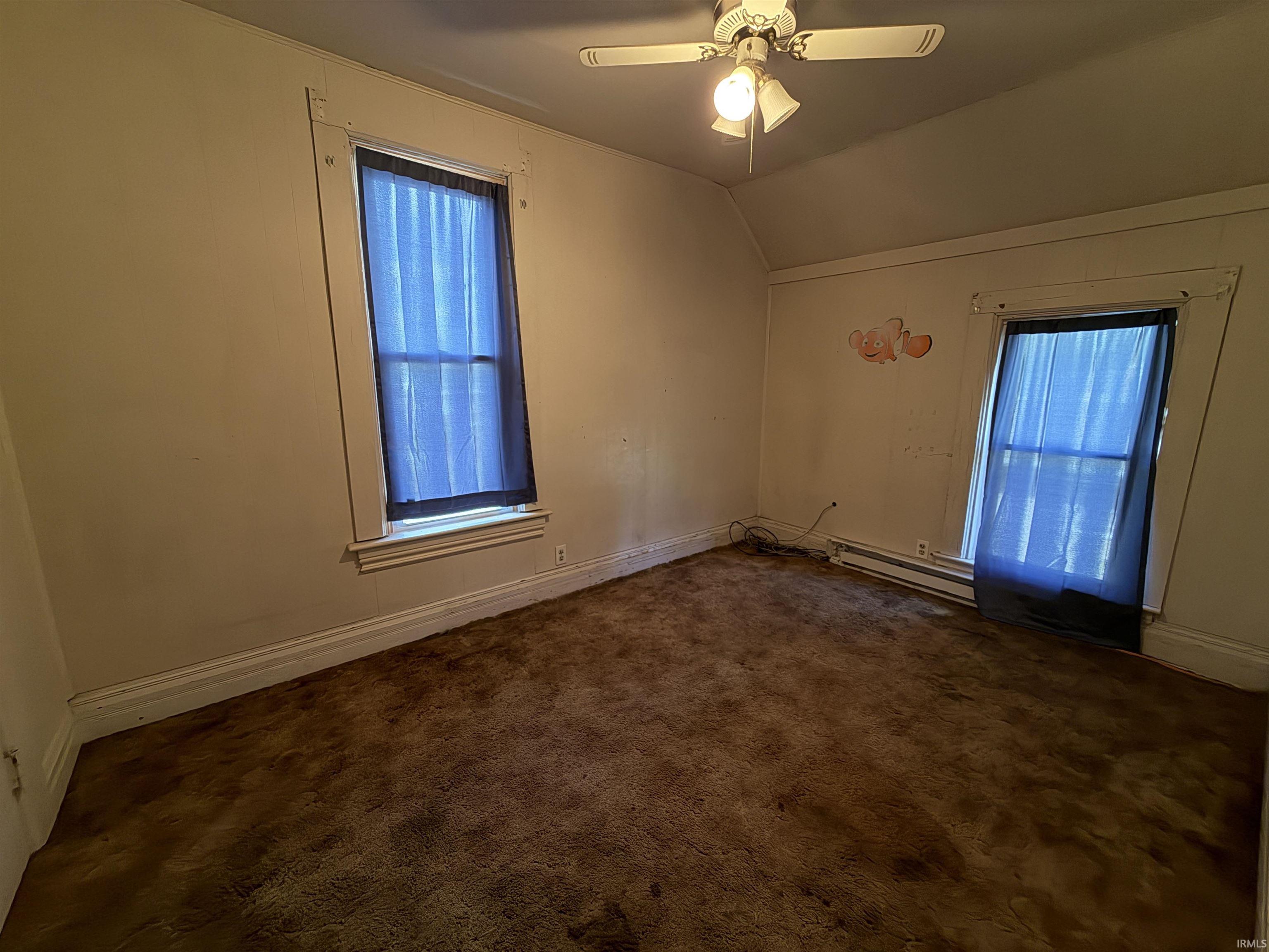 Room featuring two windows with blue coverings, a ceiling fan with integrated lighting, and carpeted flooring