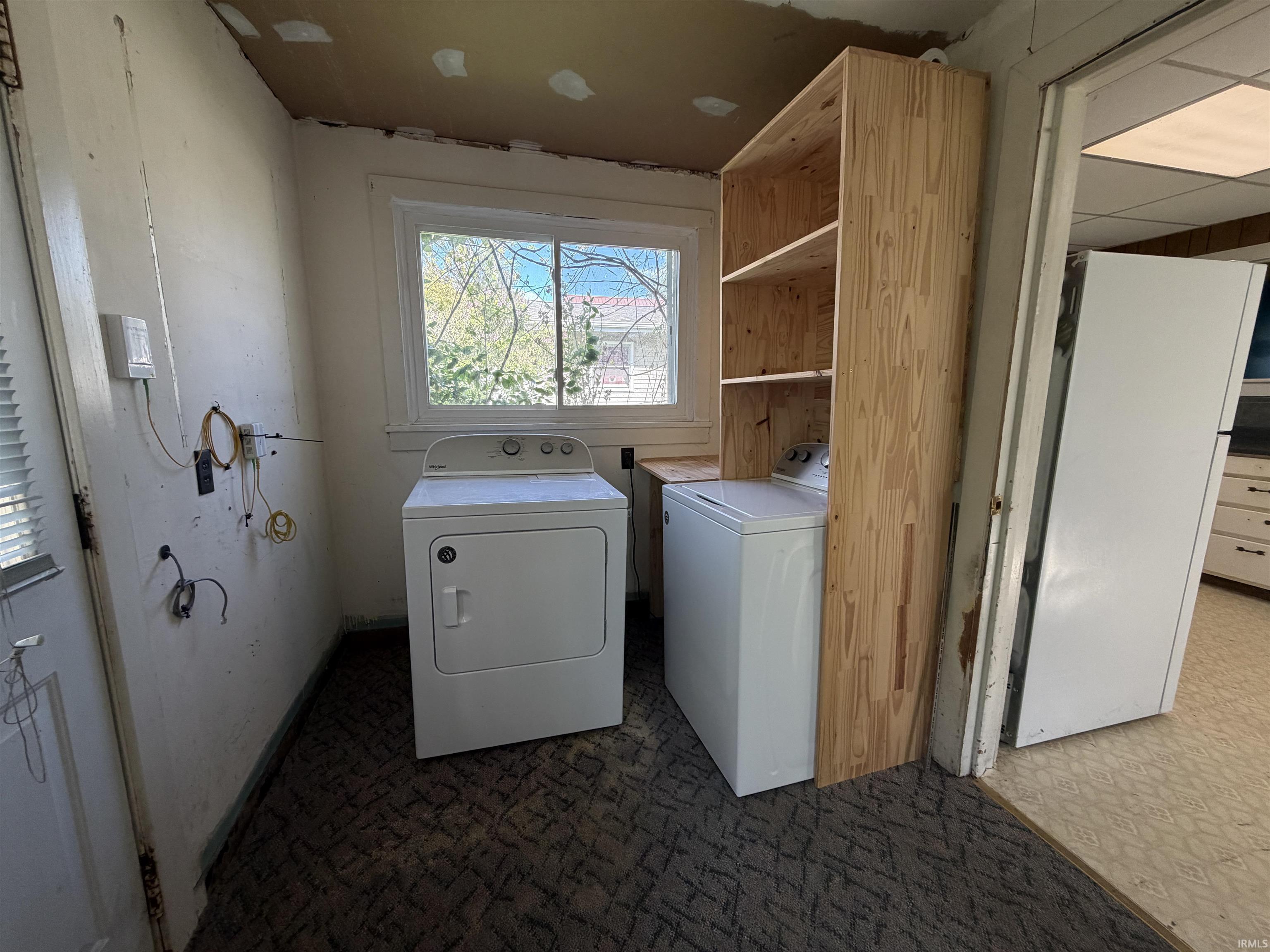 Laundry area featuring a window, built-in wooden shelving, and a light-colored door