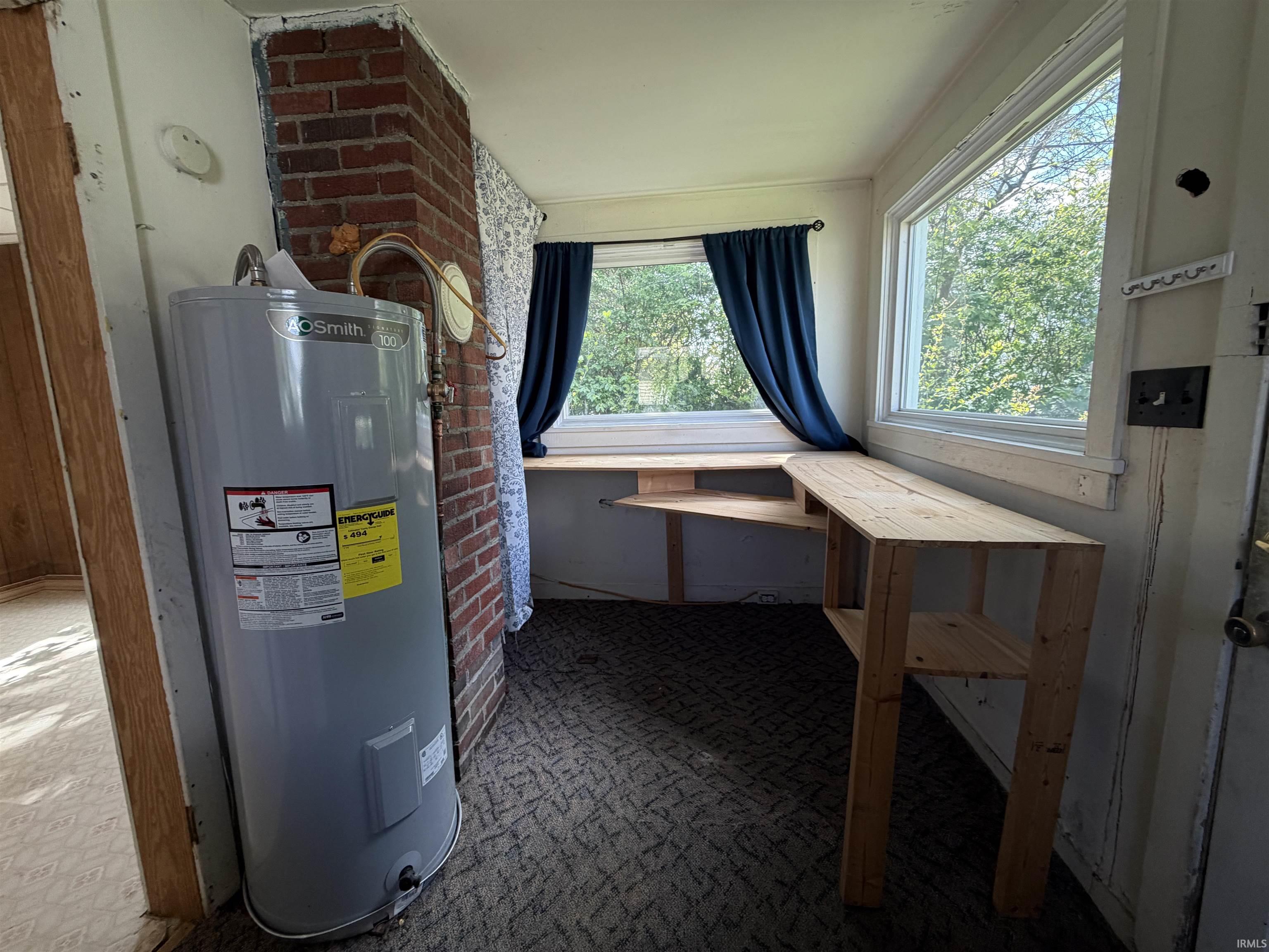 Corner room featuring a built-in wooden desk, brick wall accent, and multiple windows providing natural light