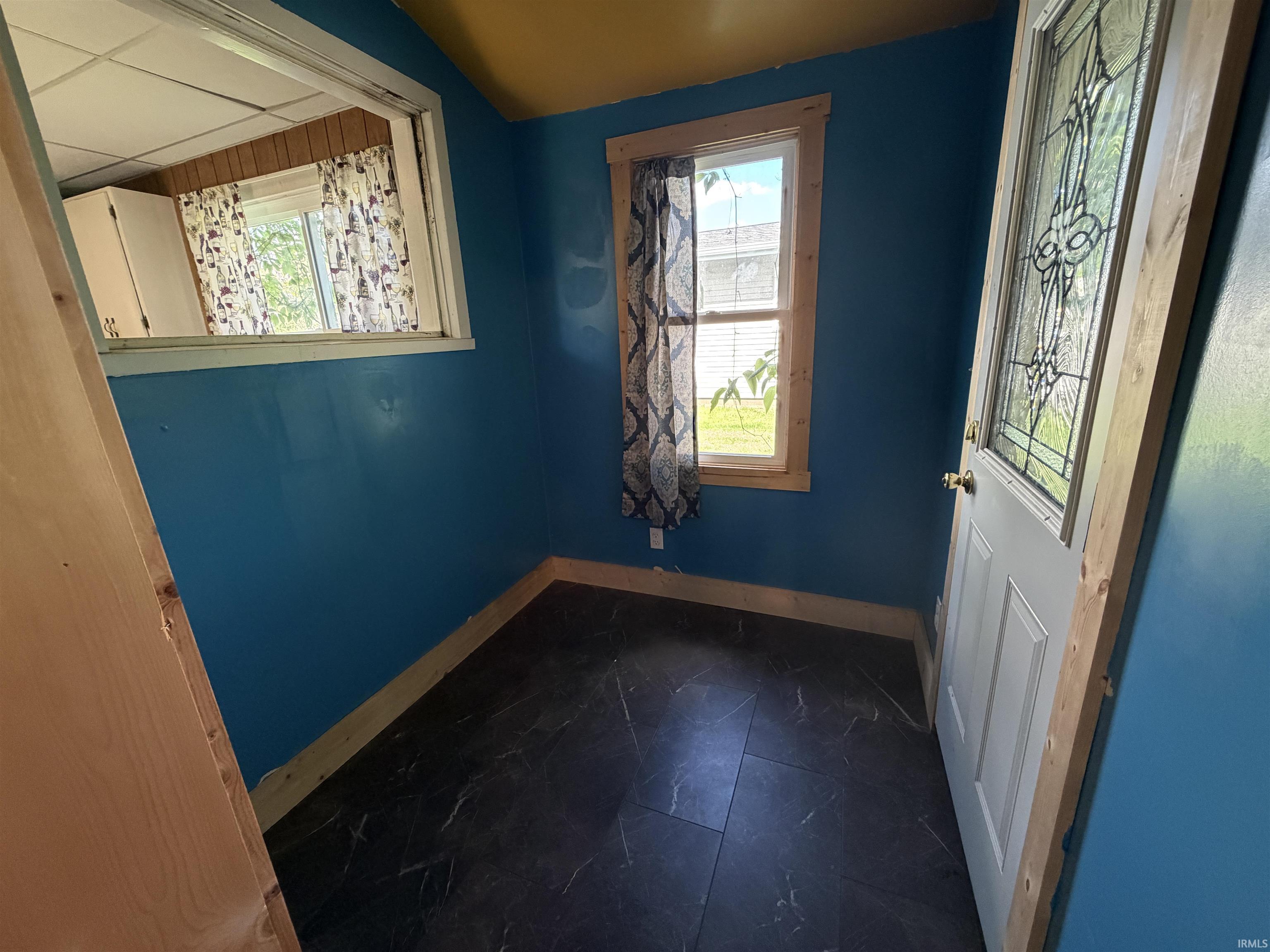 Entryway featuring dark tile flooring, a window with natural light, and an exterior door with decorative glass