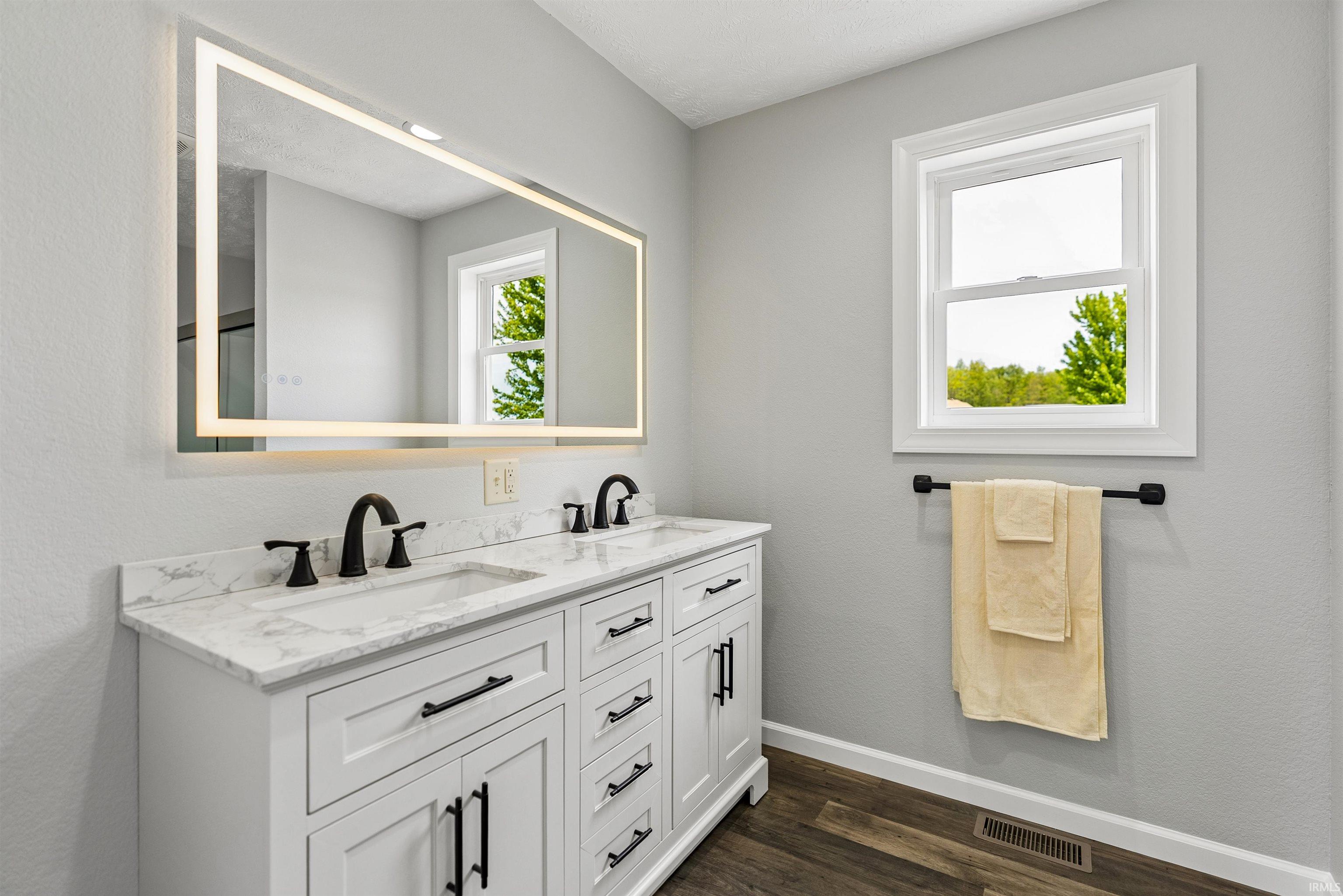 Double vanity with white cabinetry, matte black hardware, and a stone-finish countertop
