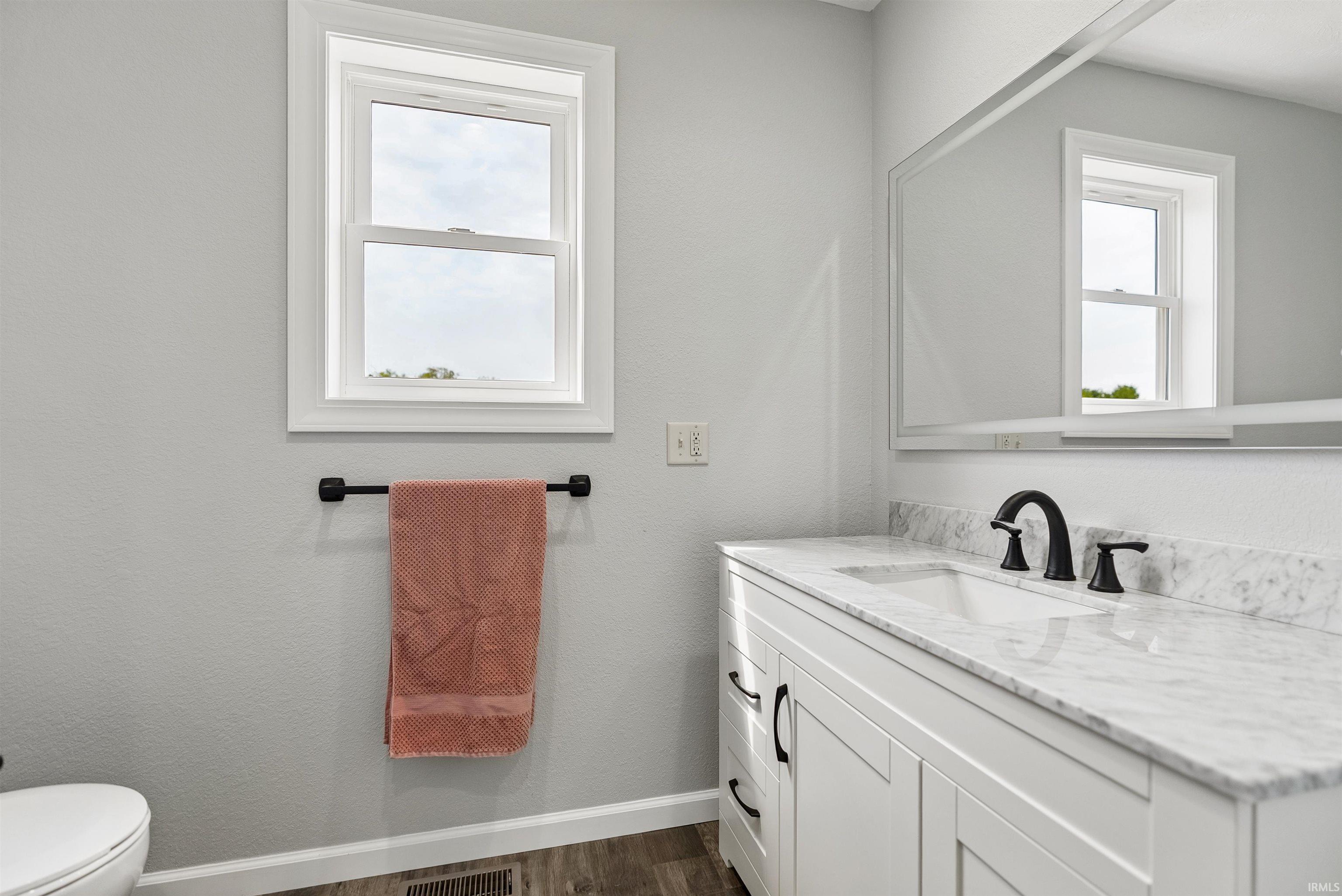 Bathroom featuring a white vanity with shaker-style cabinetry, a white countertop with integrated sink, and matte black fixtures