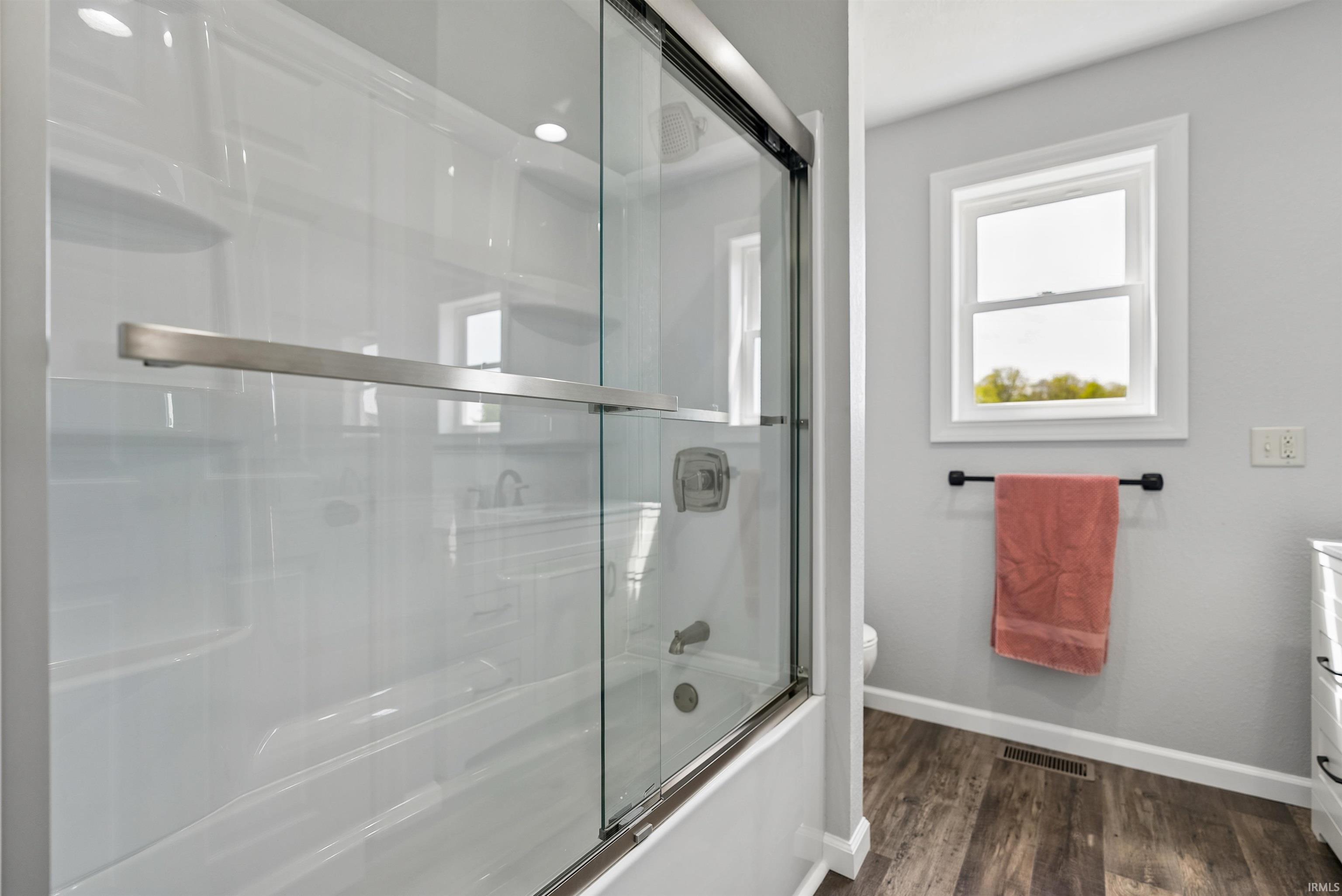 Bathroom featuring a white tub with clear glass sliding doors and brushed nickel hardware