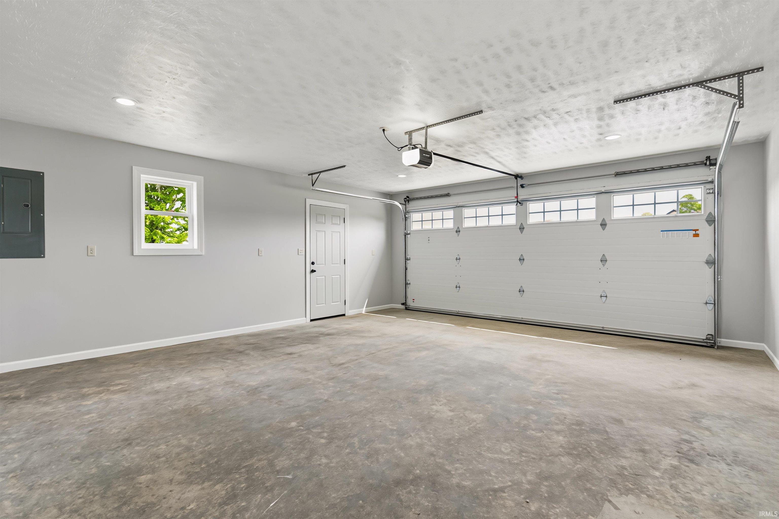 Spacious garage featuring a large overhead door with window inserts, concrete flooring, and recessed lighting