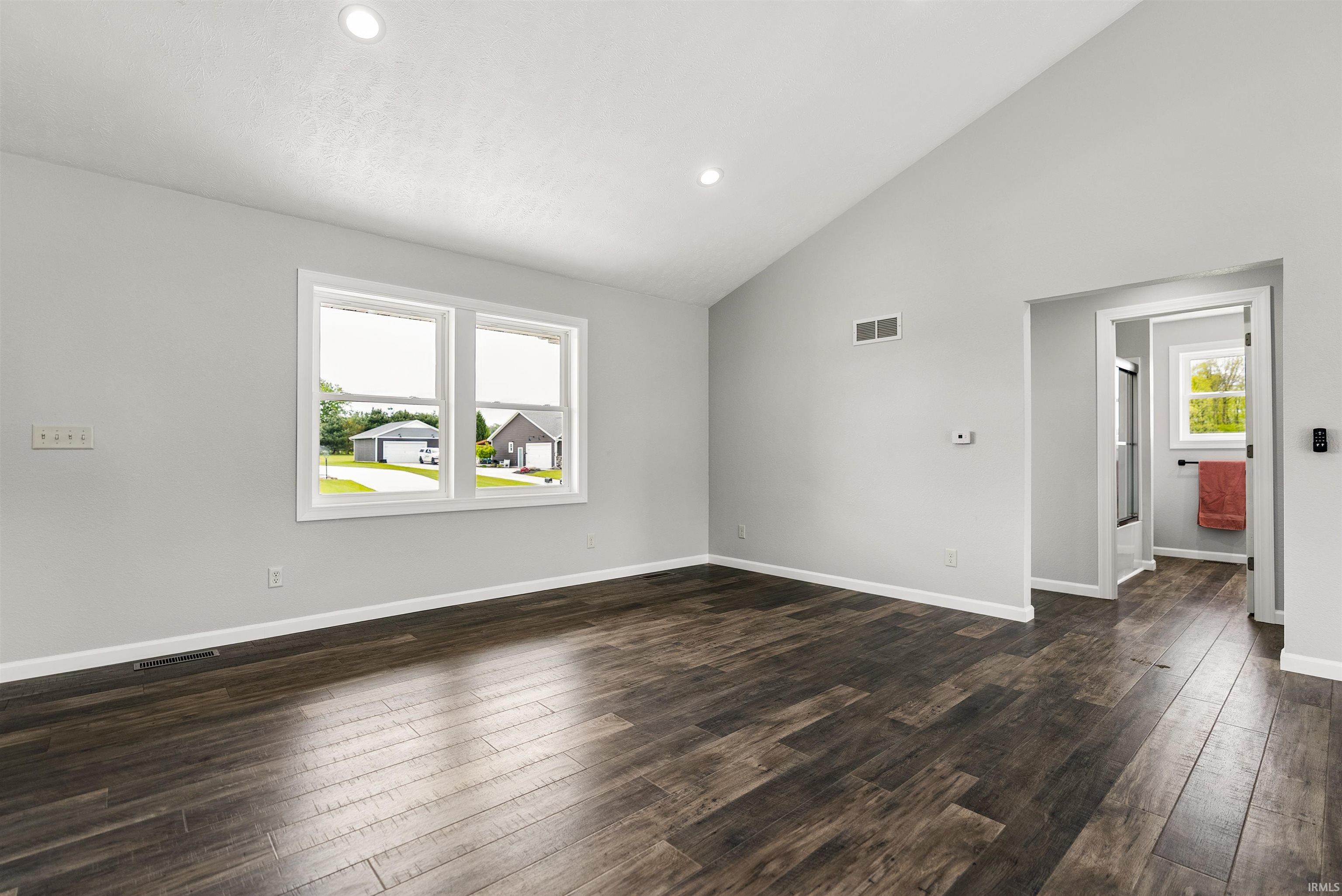 Spacious interior featuring a vaulted ceiling and wood-finish flooring