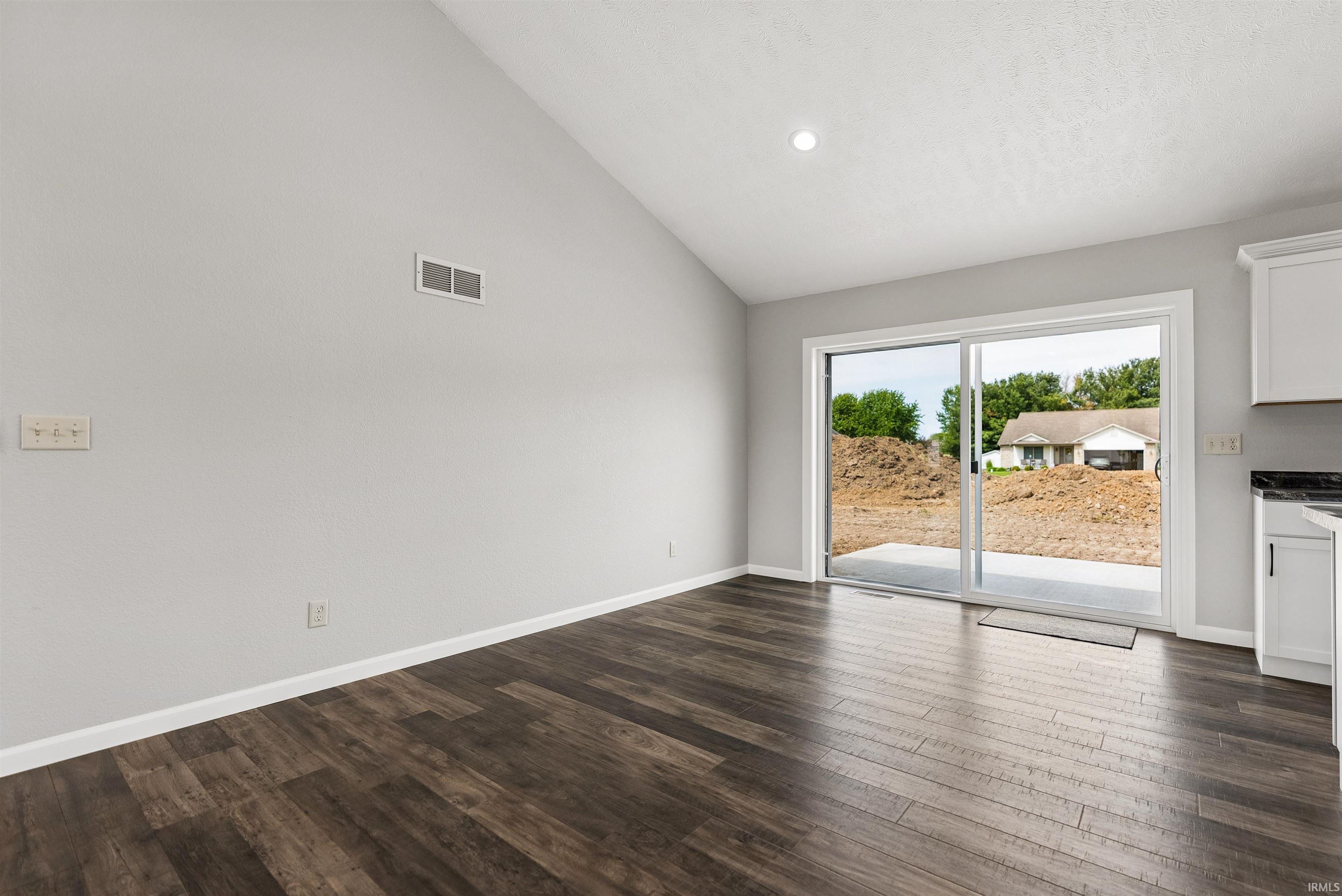 Vaulted ceiling with recessed lighting, wood-finish flooring, and white baseboards