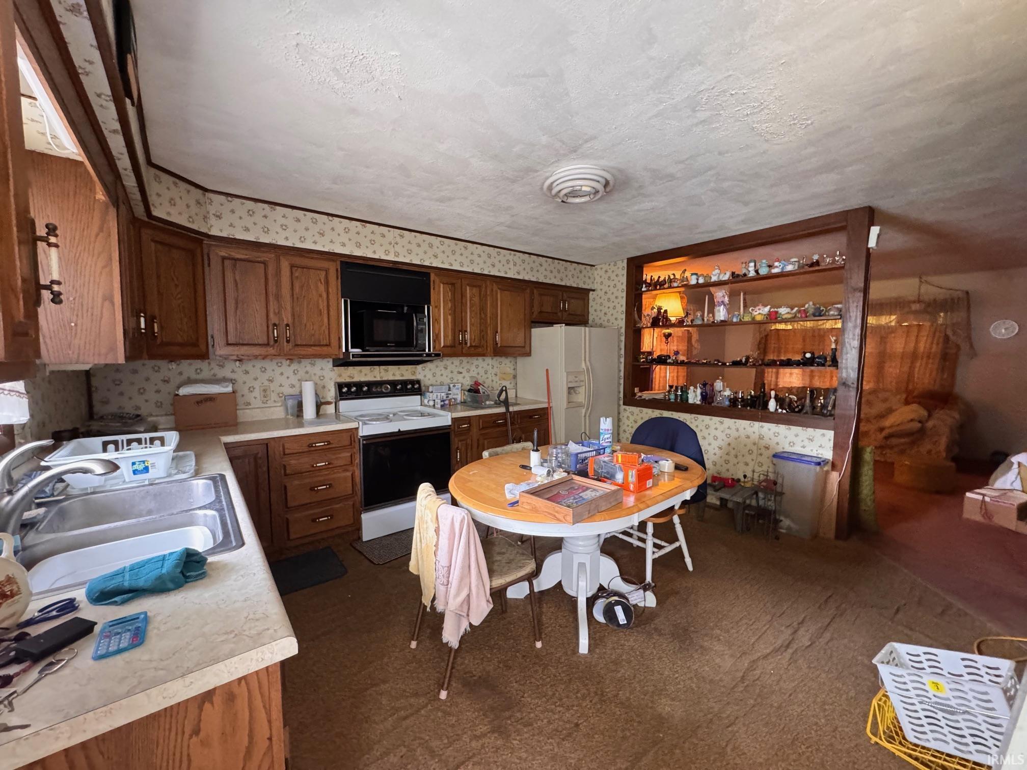 Kitchen area featuring wood cabinetry, laminate countertops, and a double basin stainless steel sink