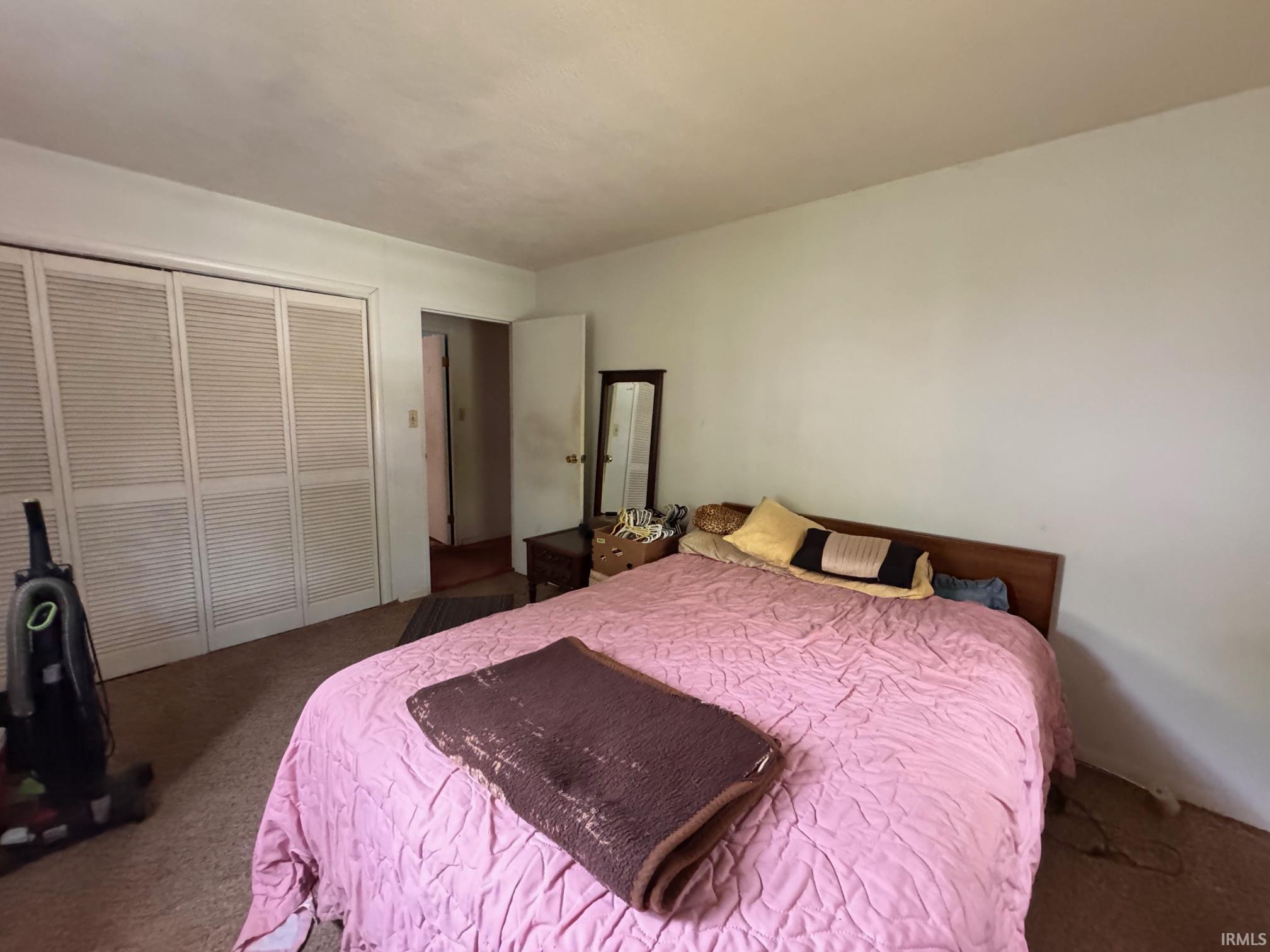 Bedroom featuring white walls, carpet flooring, and louvered bifold closet doors