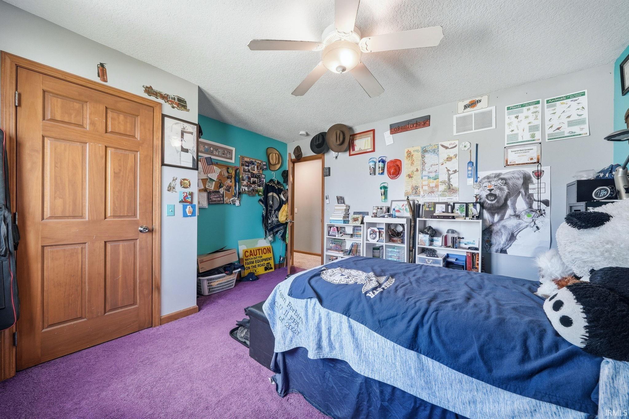 Bedroom featuring warm wood-finish panel doors, a ceiling fan with integrated lighting, and vibrant purple carpeting