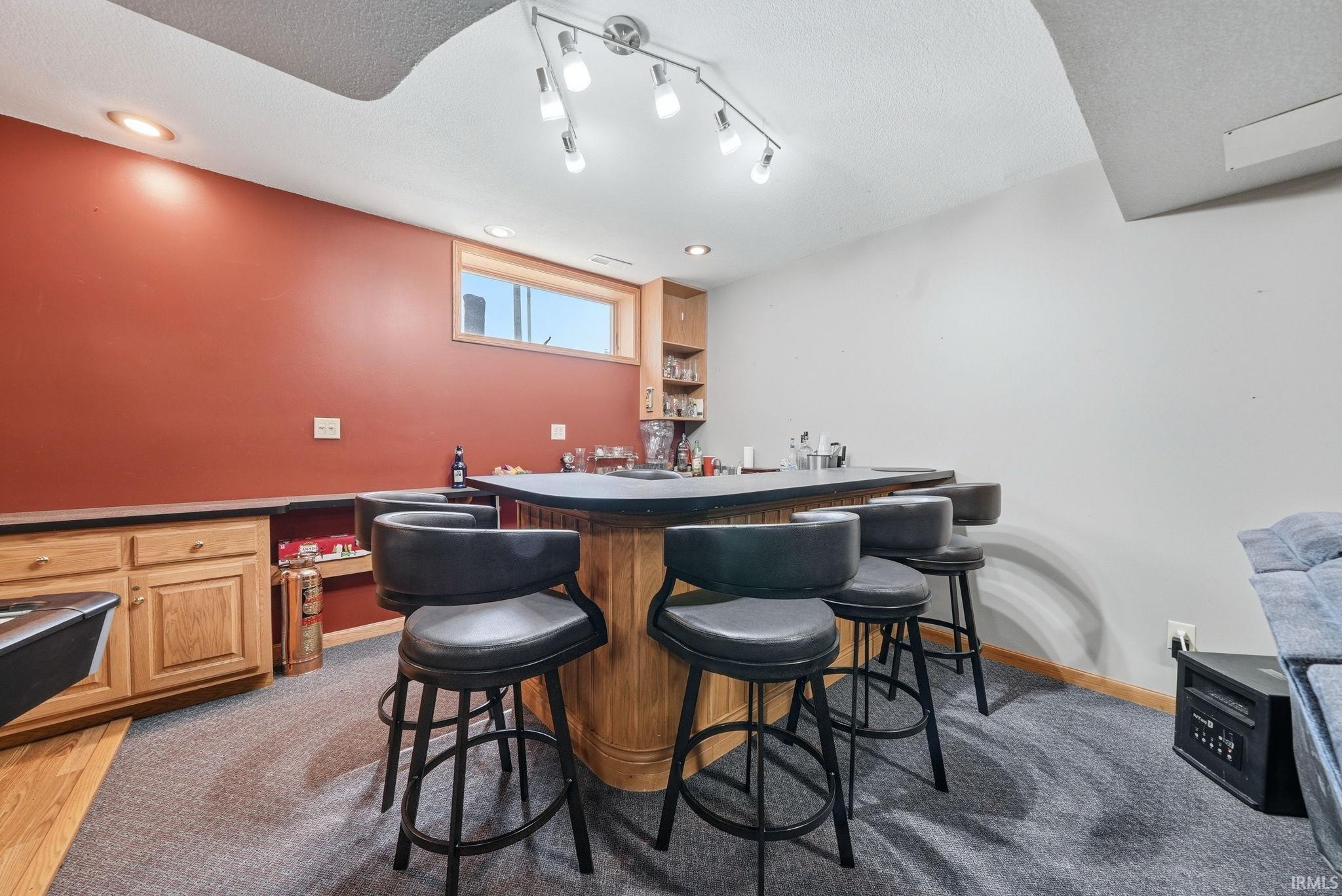 Built-in bar featuring a wood base, dark countertop, and track lighting