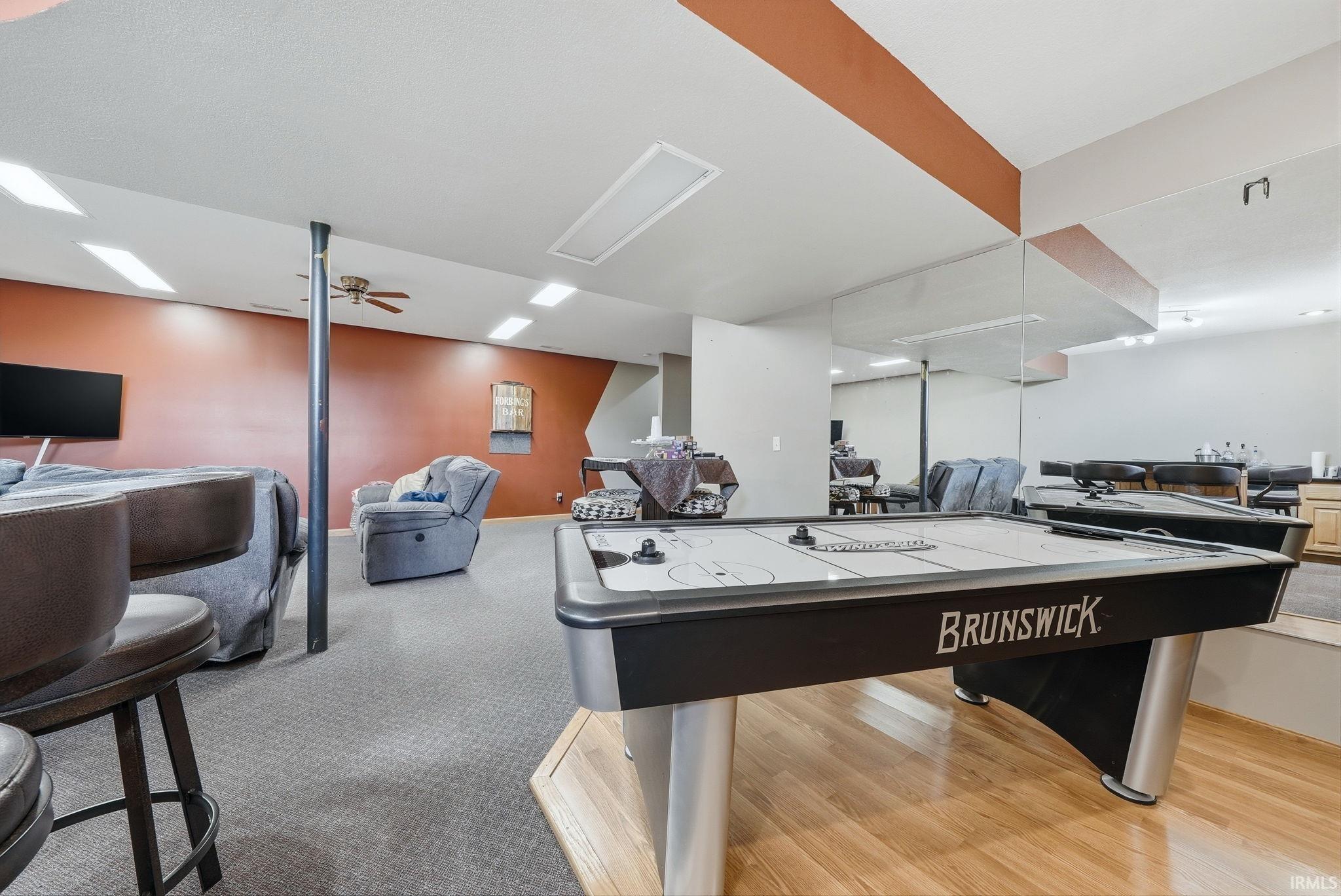 Lower-level recreation space featuring wood-finish flooring and grey carpeting