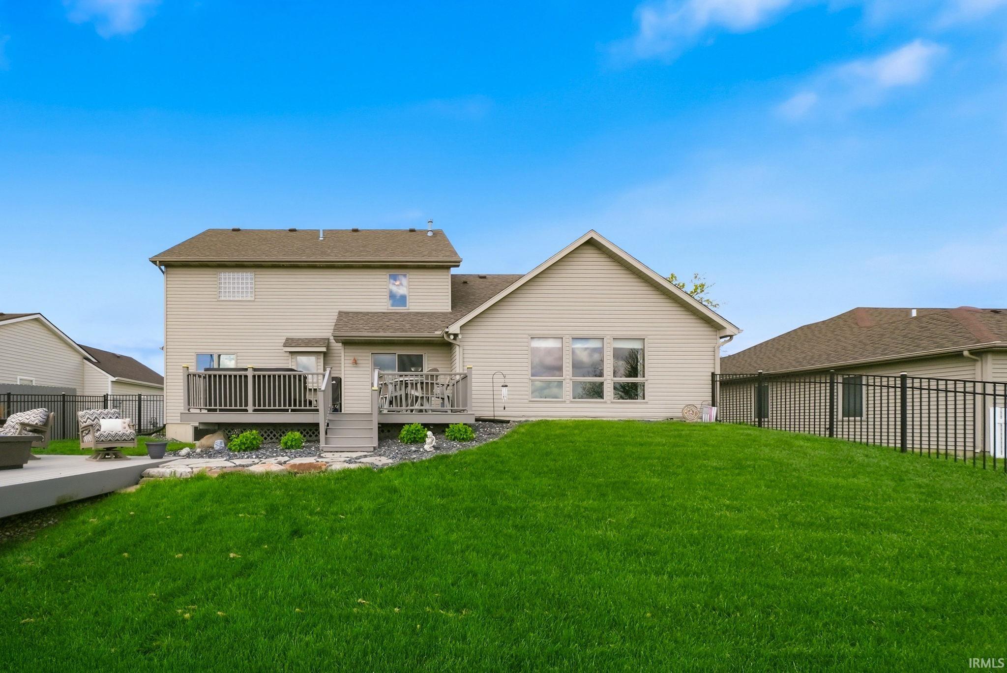 Rear exterior featuring a multi-level wood deck, a paved patio, and a sloped lawn