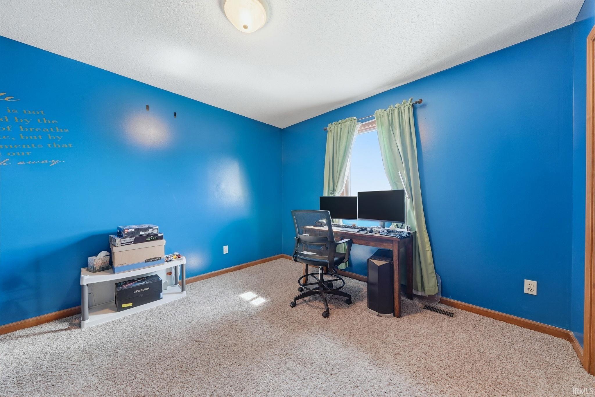 Room with blue accent walls, carpeted flooring, and a single window with drapes