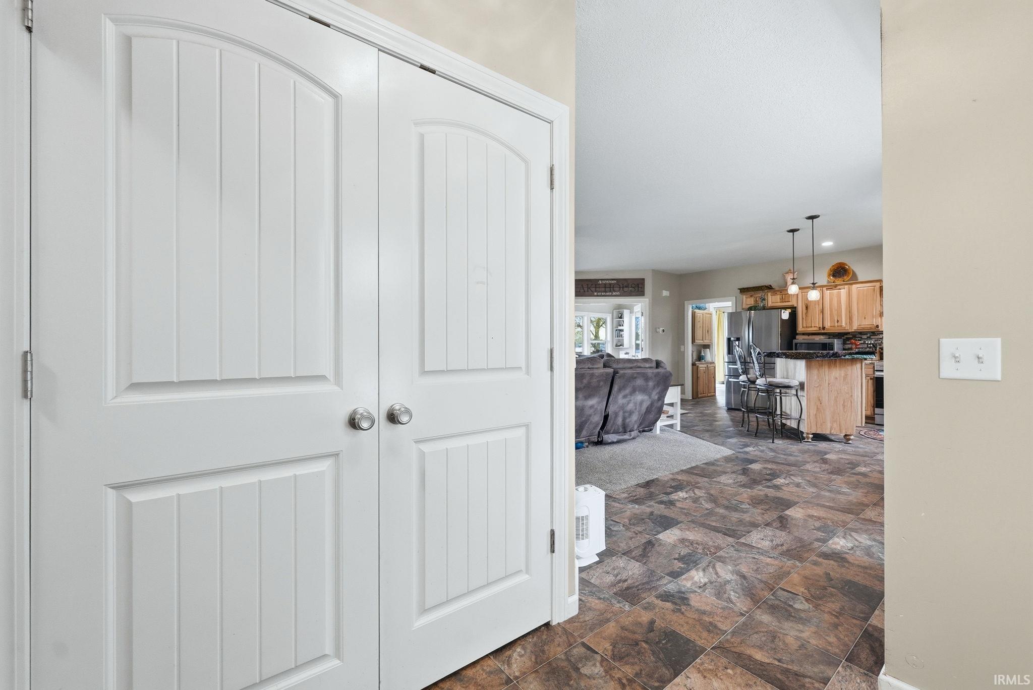 White bifold doors with arched paneling and spherical hardware open to an interior with patterned tile flooring