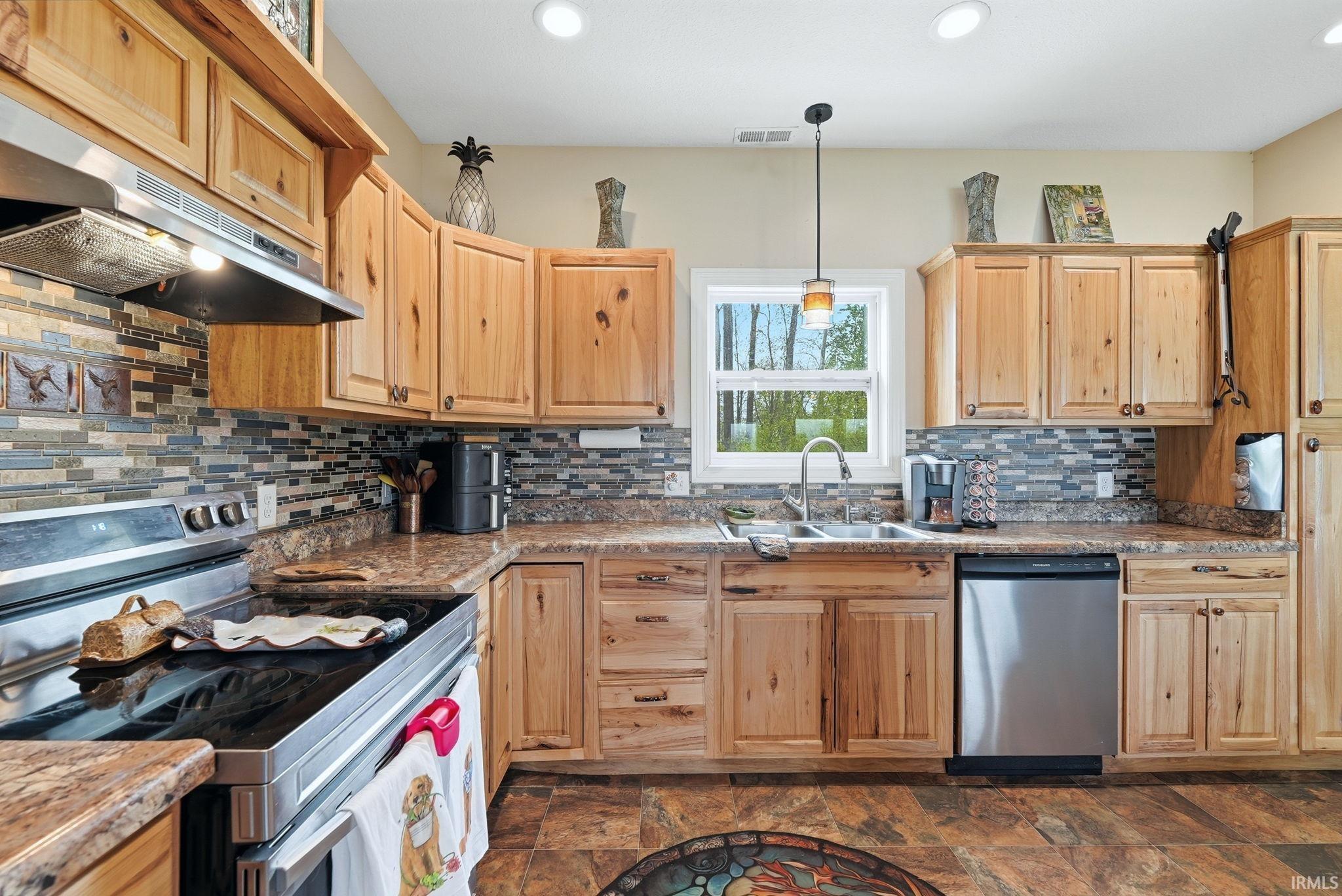 Kitchen featuring natural wood cabinetry, multi-toned tile backsplash, and wood-finish flooring