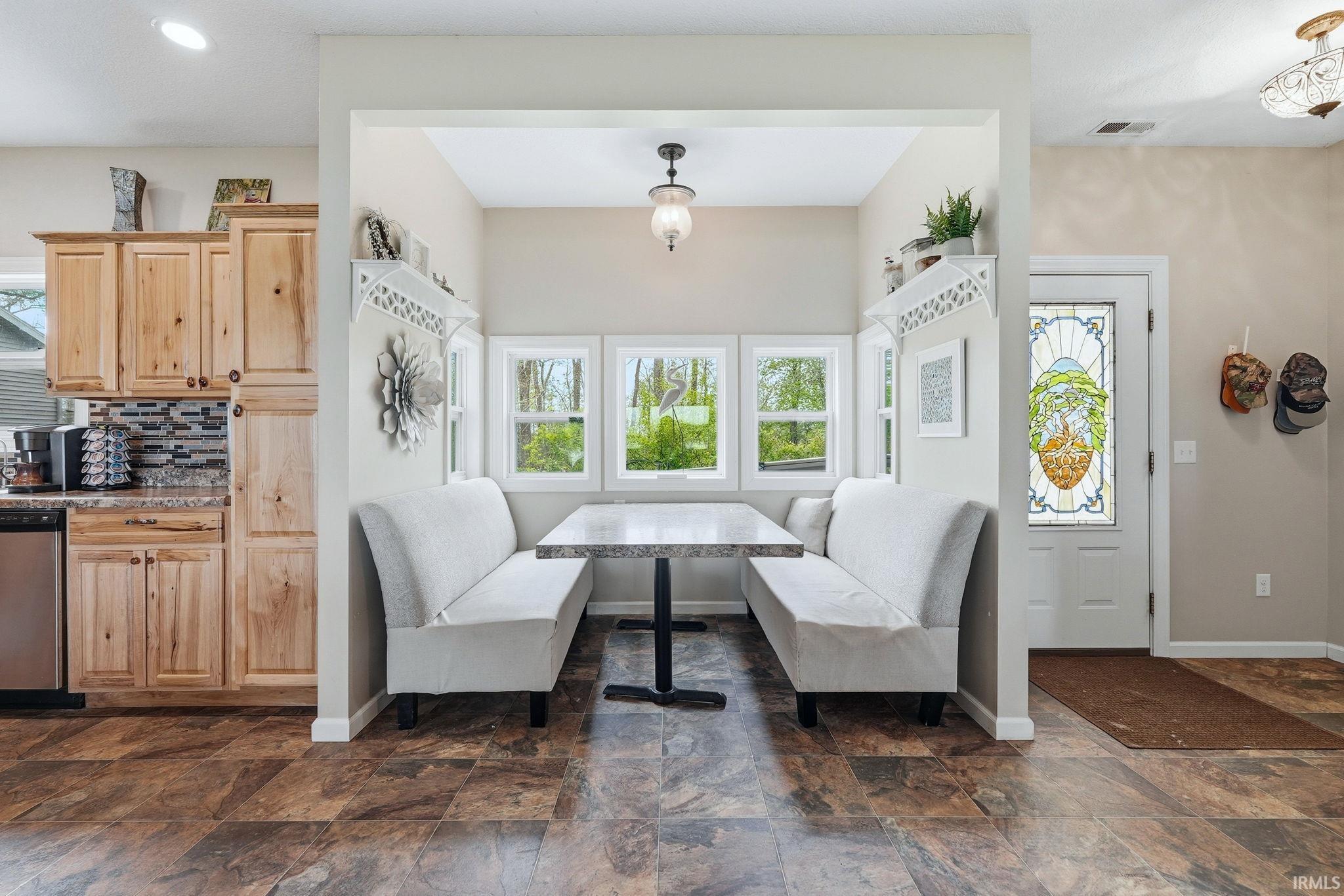 Breakfast nook featuring a built-in banquette, three windows, and a hanging light fixture