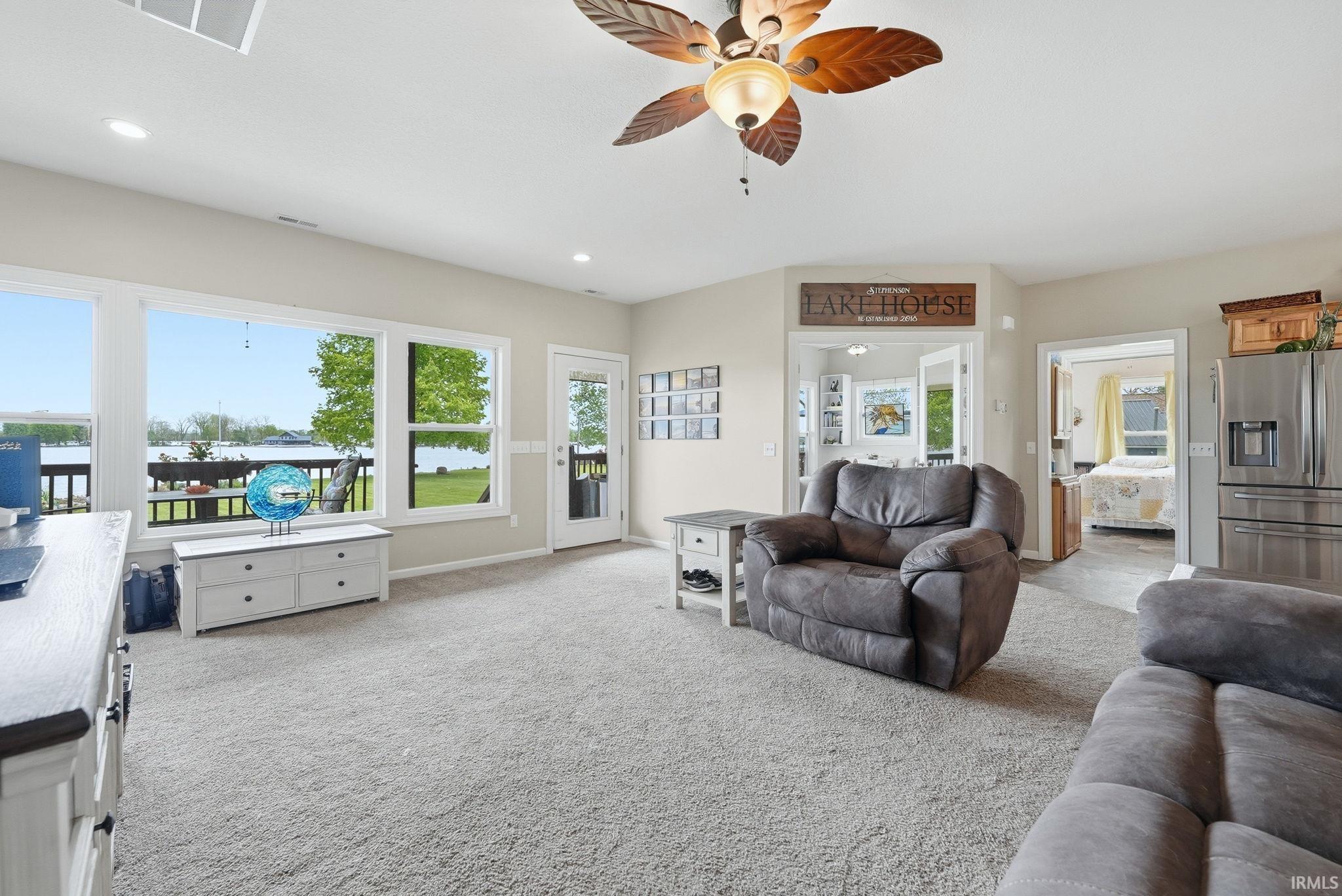 Open-concept living space featuring expansive windows and a glass-paneled door opening to an outdoor deck