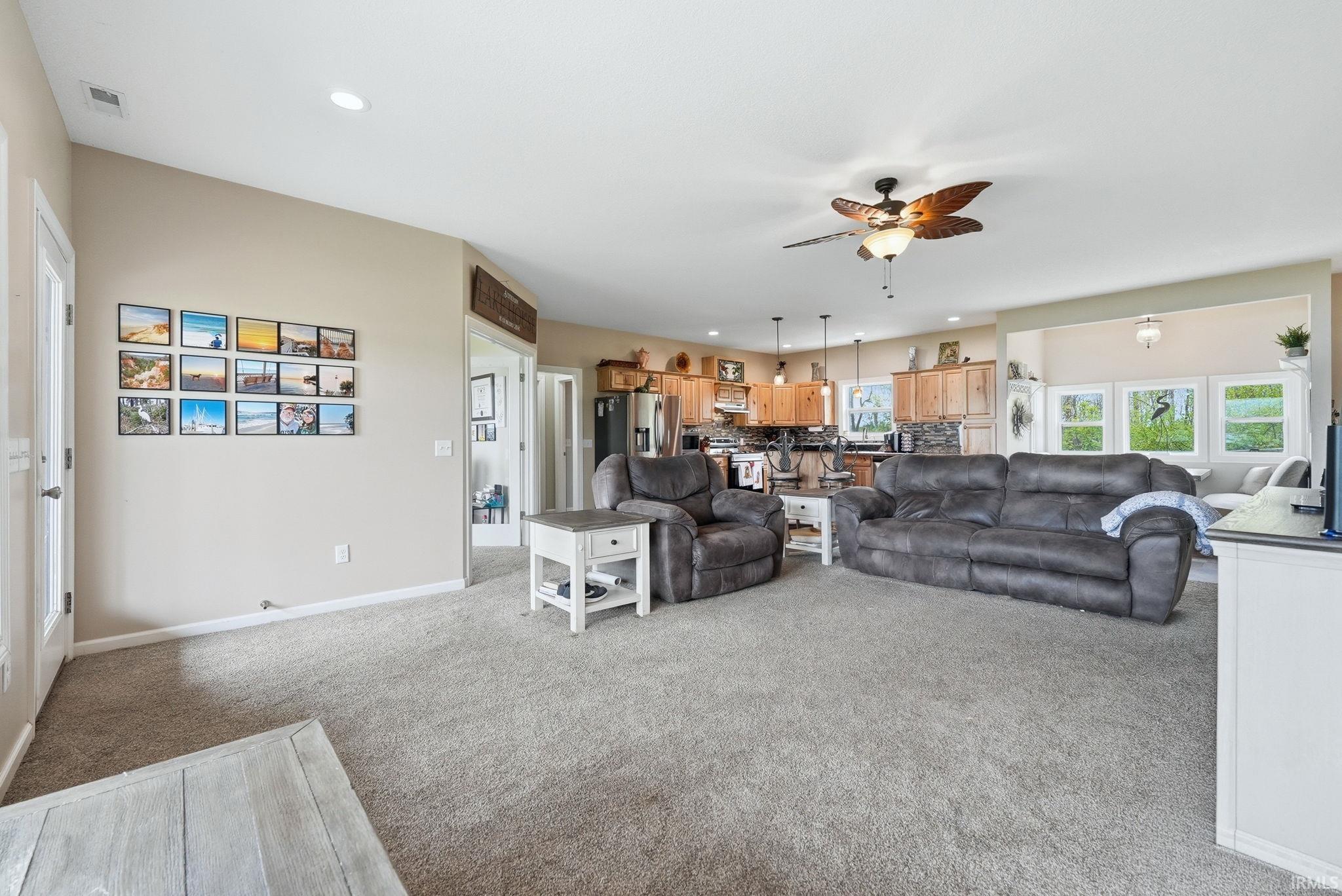 Spacious living area with neutral carpeting, recessed lighting, and a ceiling fan