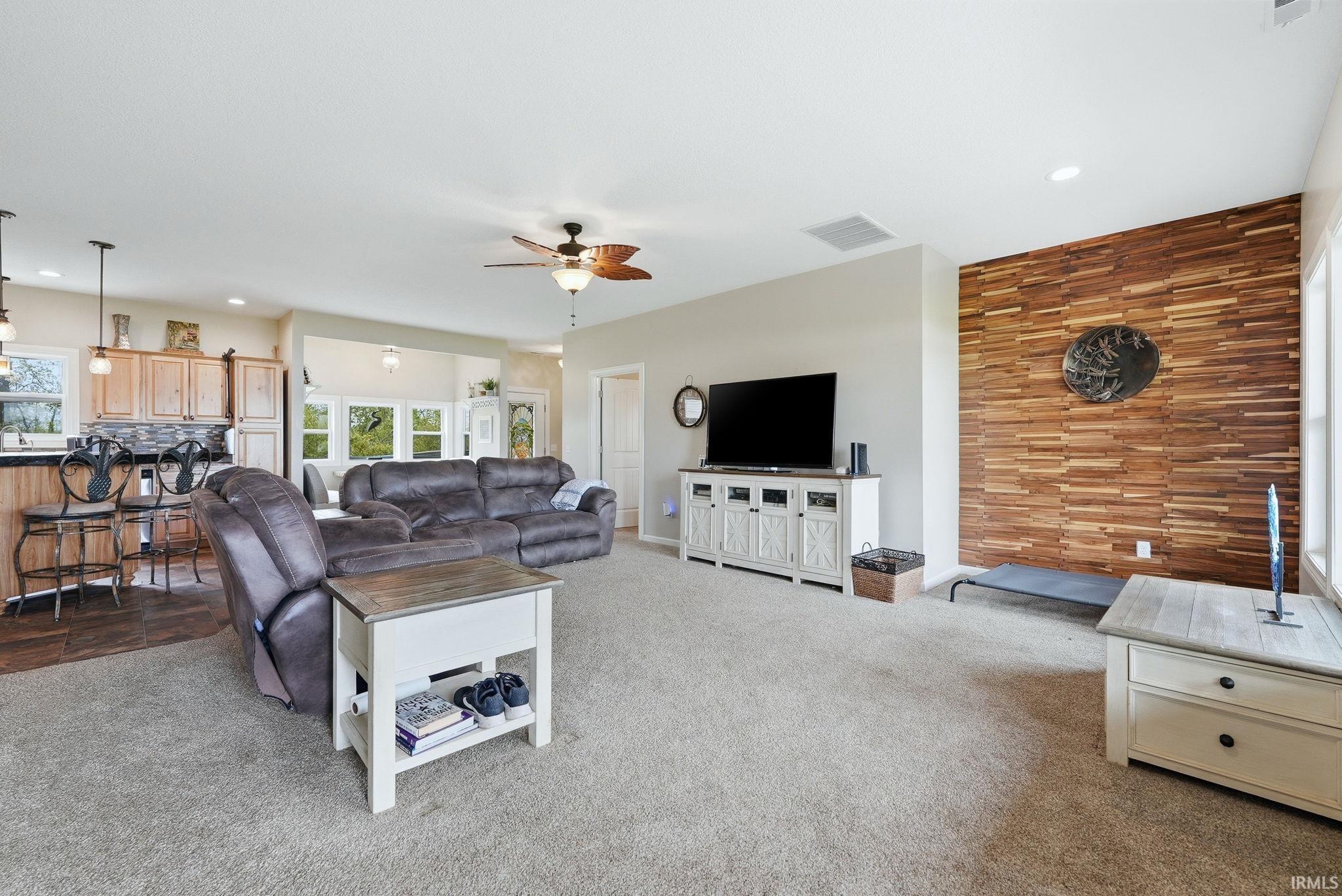 Open-concept living area with a wood-accented wall and light-colored carpeting