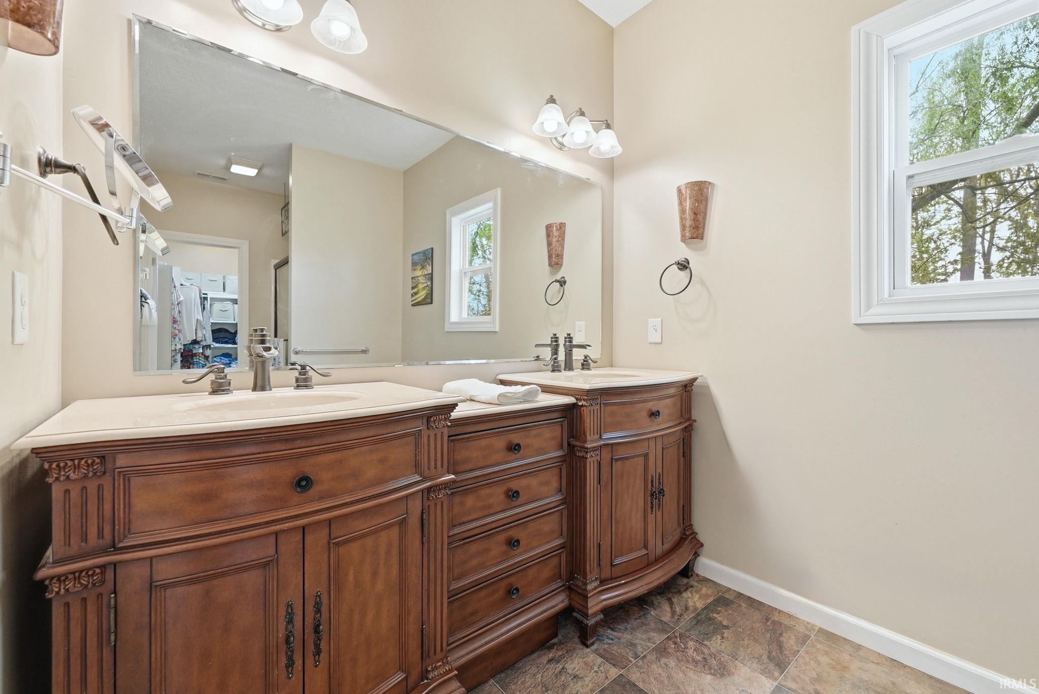 Dual vanity featuring wood-finish cabinetry, integrated sinks, and neutral countertops