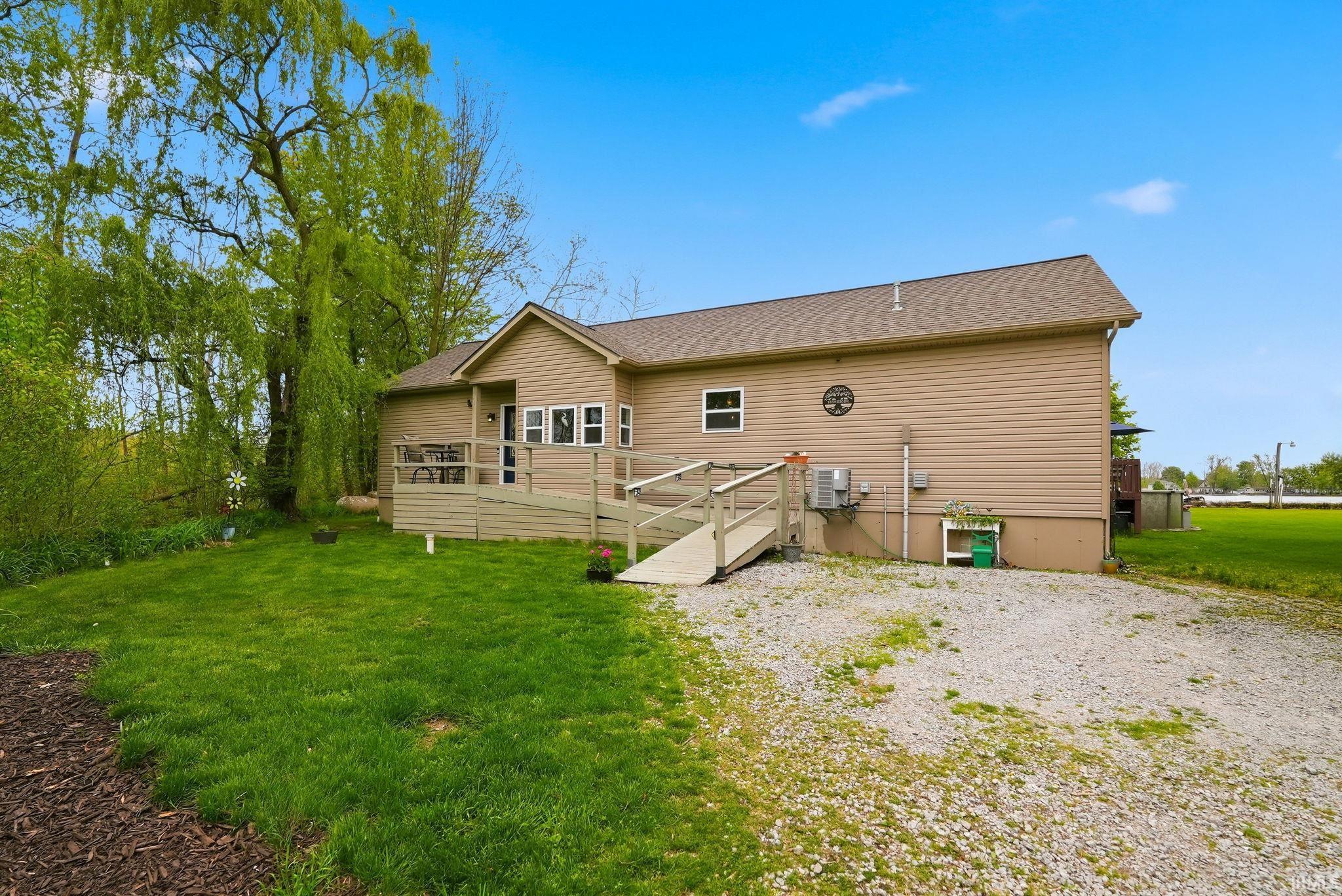 Exterior with tan siding, a brown shingle roof, and a gravel driveway