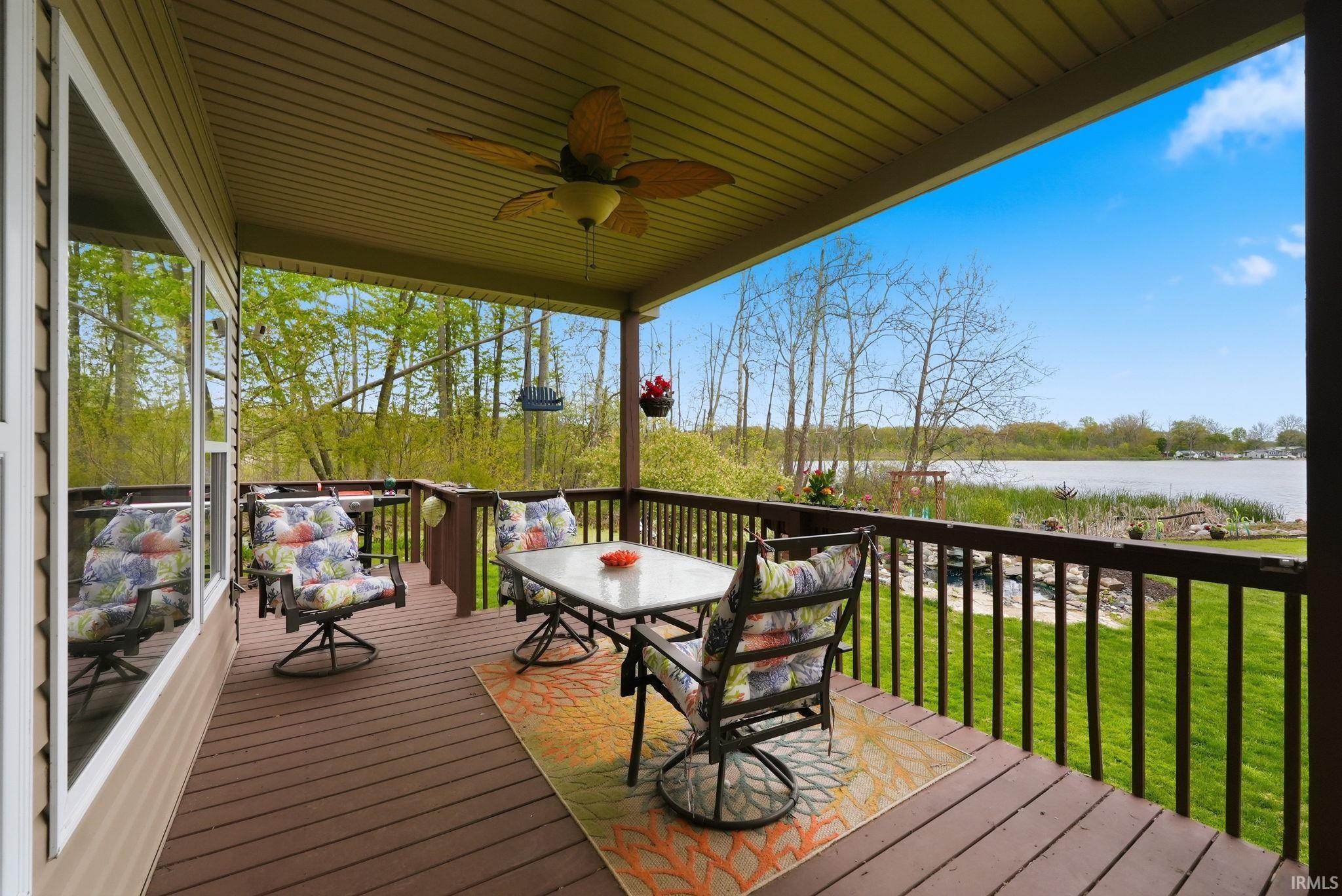 Covered deck featuring wood-finish flooring, a ceiling fan, and a painted wood railing