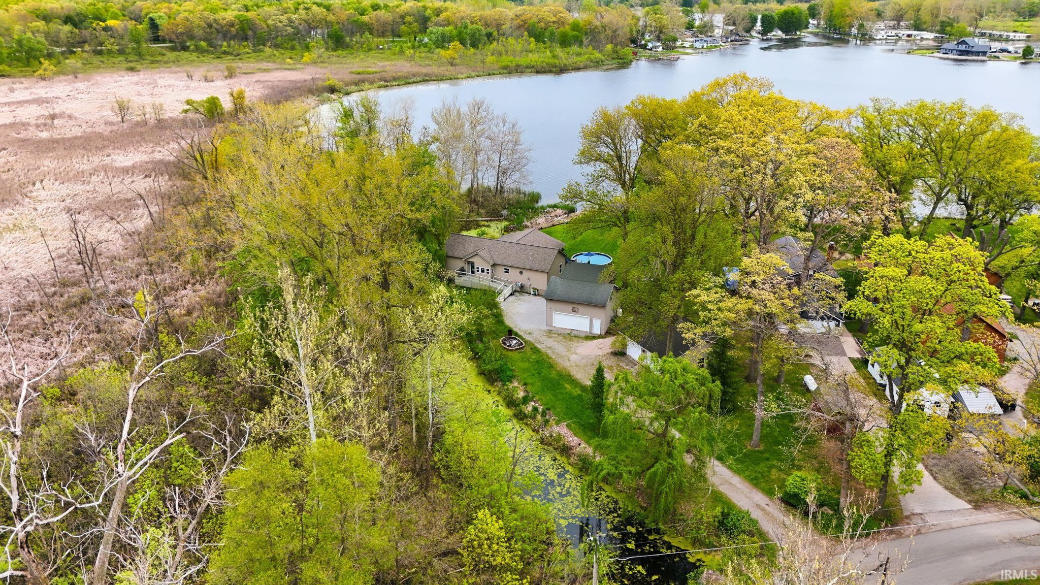 Waterfront property featuring a residential structure, a detached garage, and a round above-ground pool