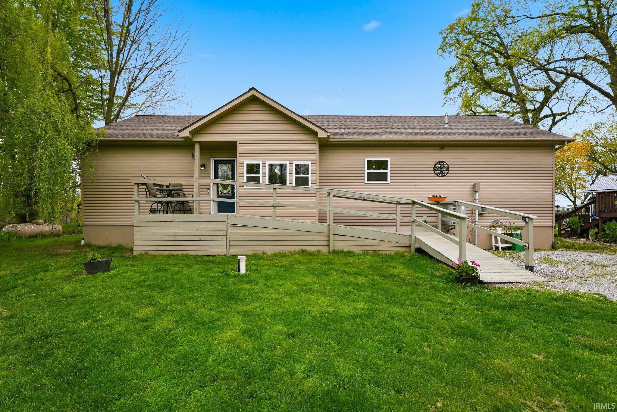 Exterior featuring tan siding, a gabled entry, and a brown shingle roof