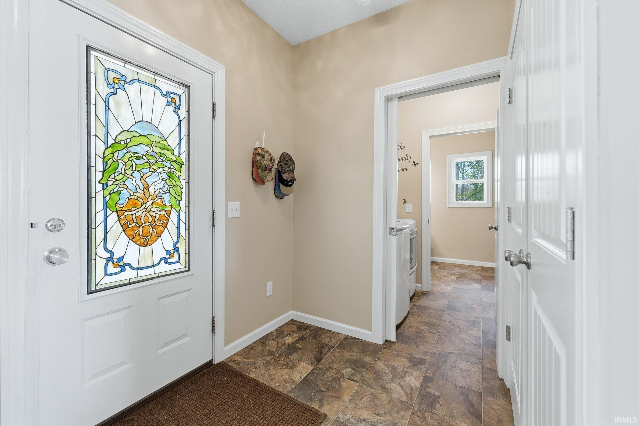 Entryway featuring a decorative stained glass door insert, warm neutral wall paint, and patterned vinyl flooring