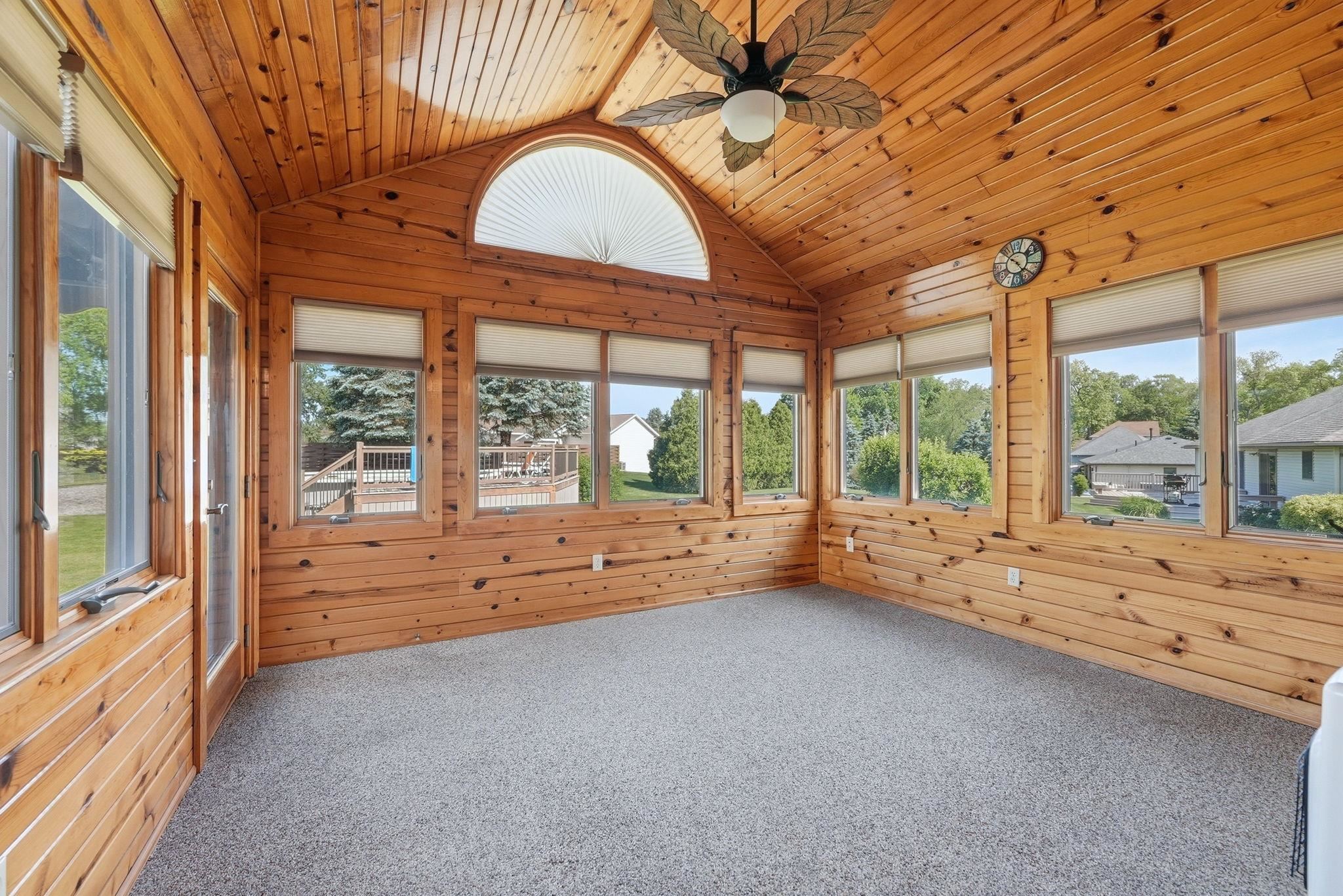 Wood-paneled sunroom featuring a vaulted ceiling and a ceiling fan
