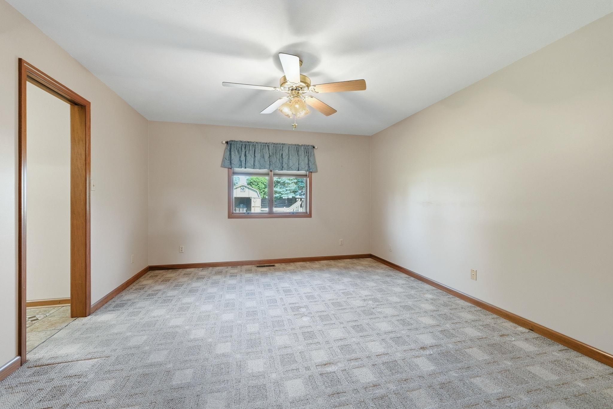 Spacious room featuring patterned carpet flooring, light-toned walls, and wood trim