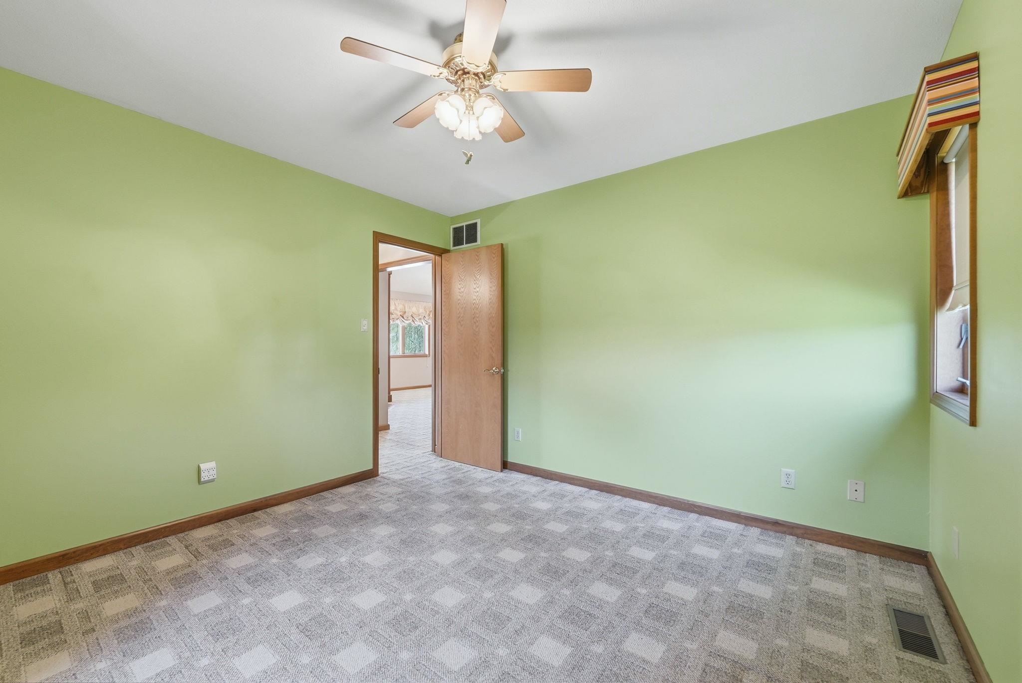 Room featuring light green walls, patterned gray carpet, and wood trim