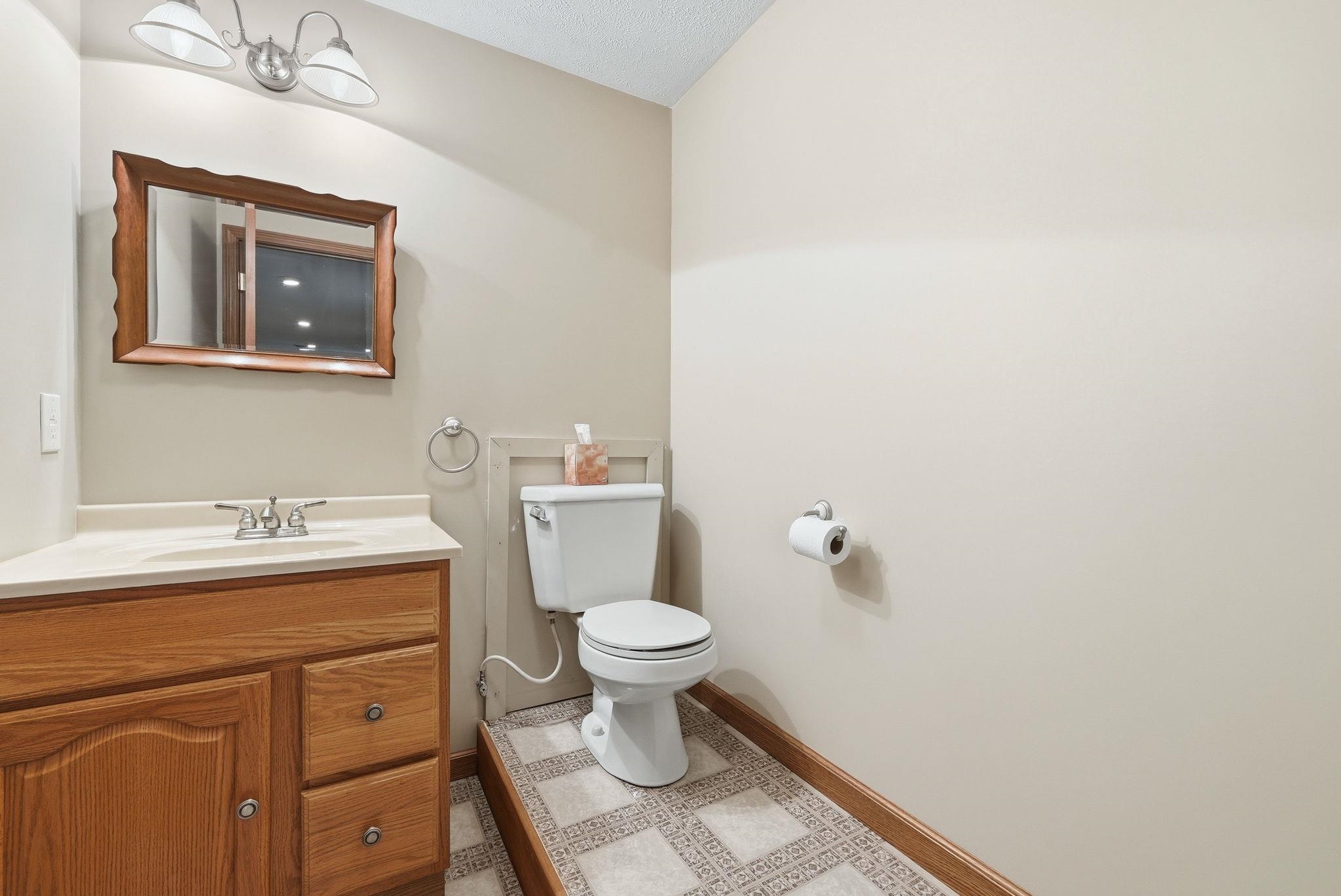 Bathroom featuring a wood-finish vanity with a single sink, an integrated countertop, and a decorative framed mirror