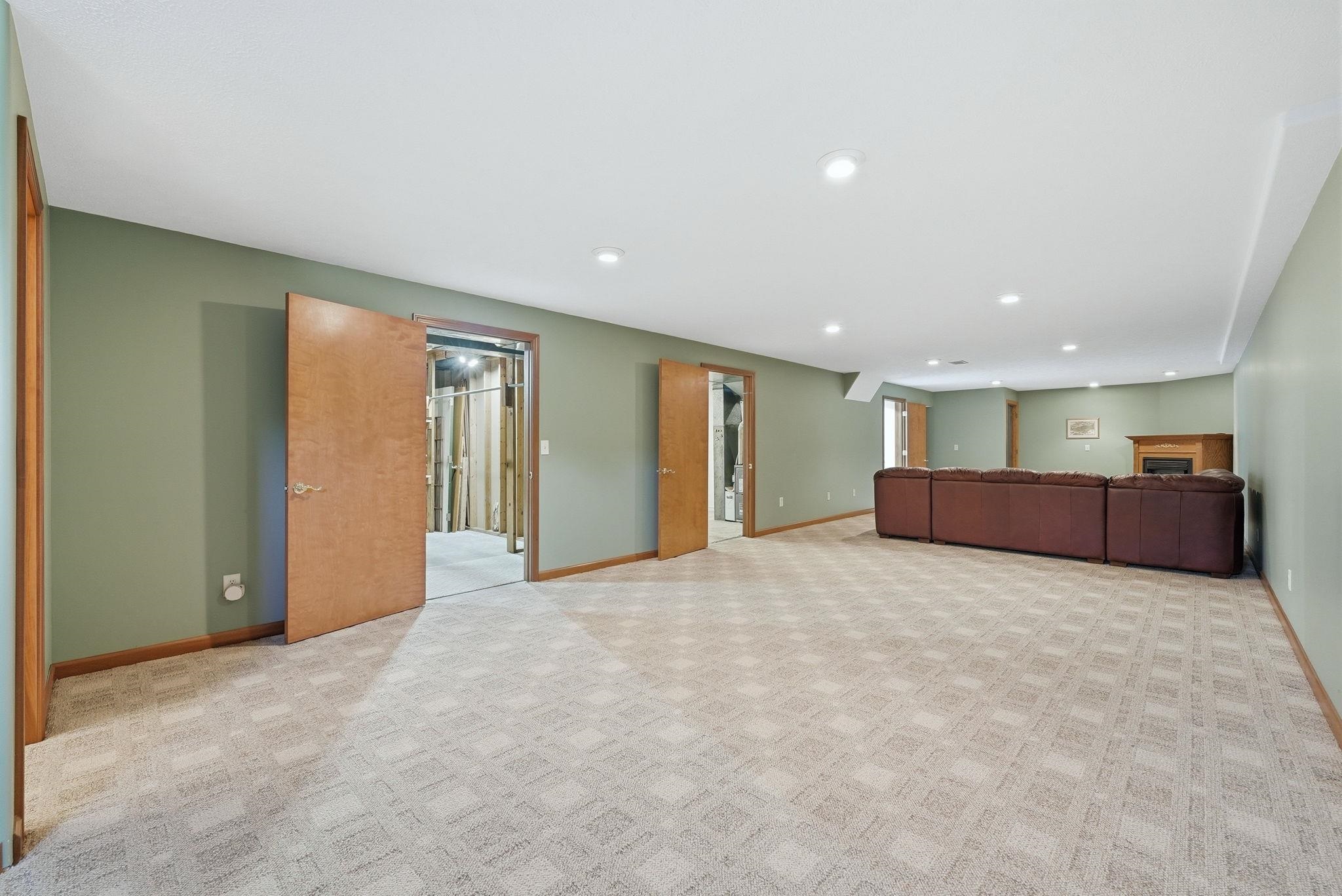 Spacious finished basement with recessed lighting, green accent walls, and patterned carpet