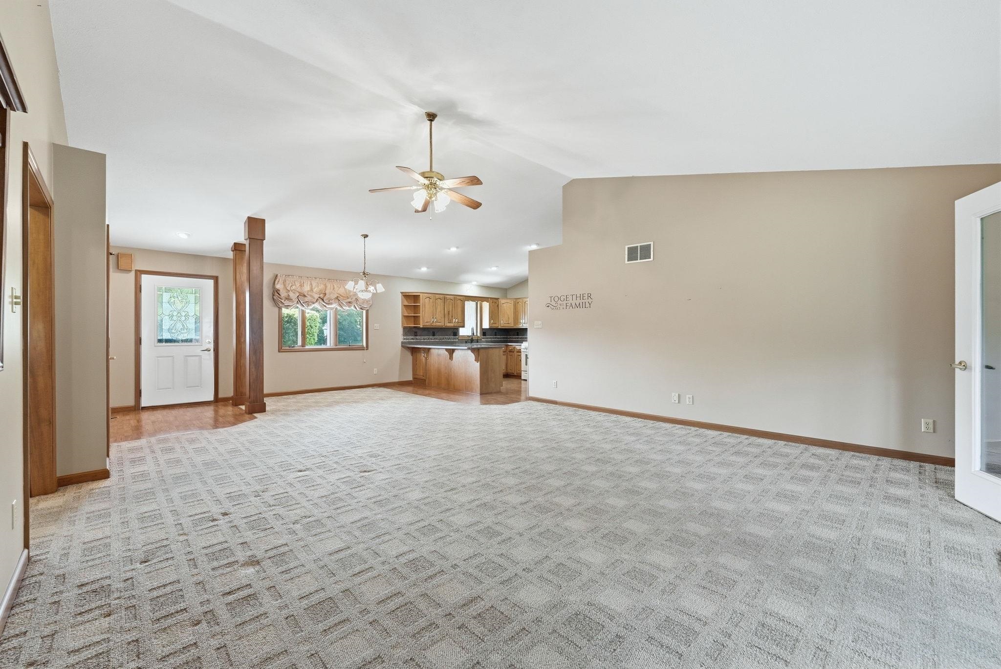 Expansive living area with vaulted ceilings and patterned carpet flooring