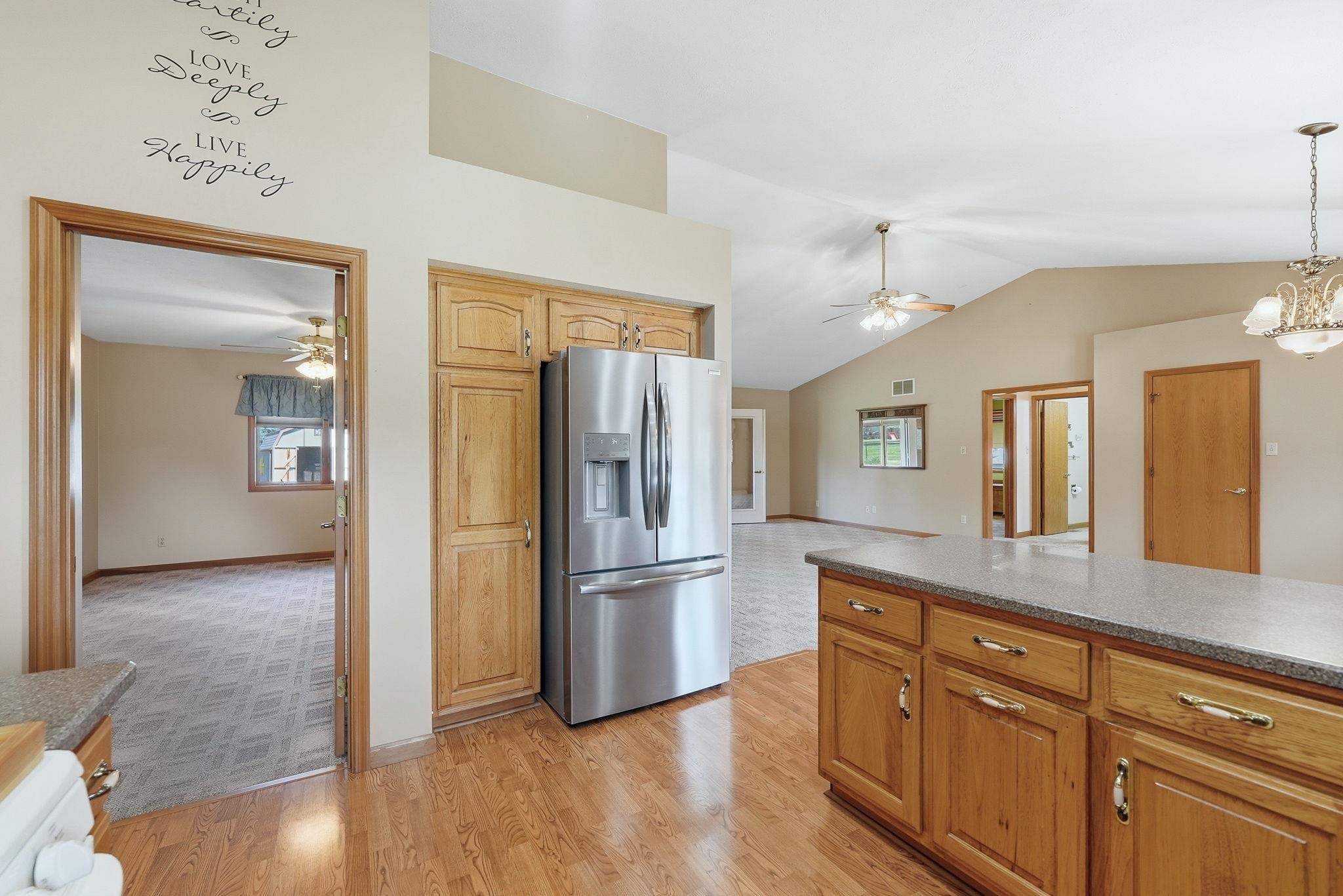 Kitchen island with wood-finish cabinetry, stone-look countertop, and integrated stainless steel refrigerator