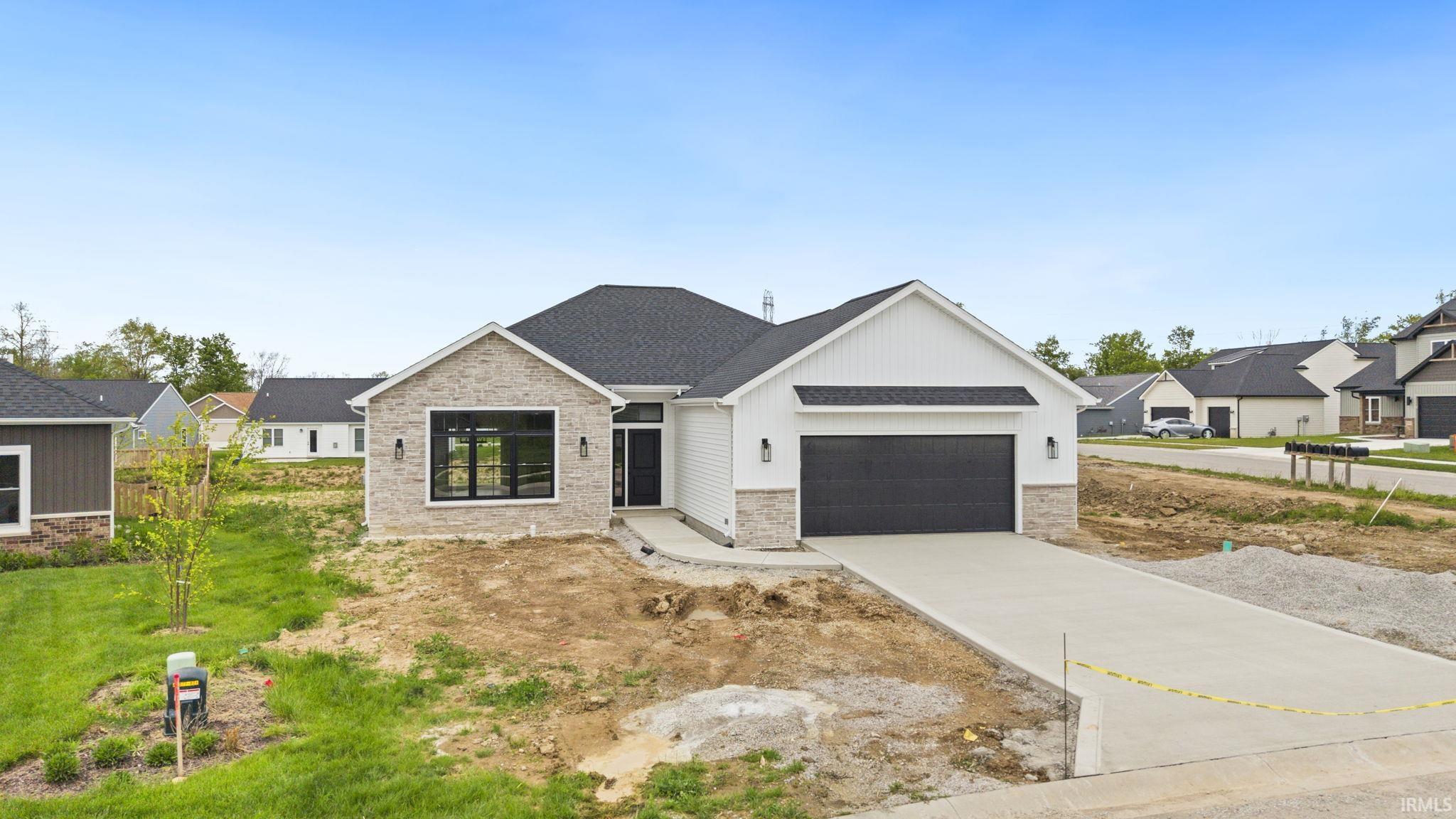 New construction residence featuring a dark asphalt shingle roof, white vertical siding, and light-toned brick accents
