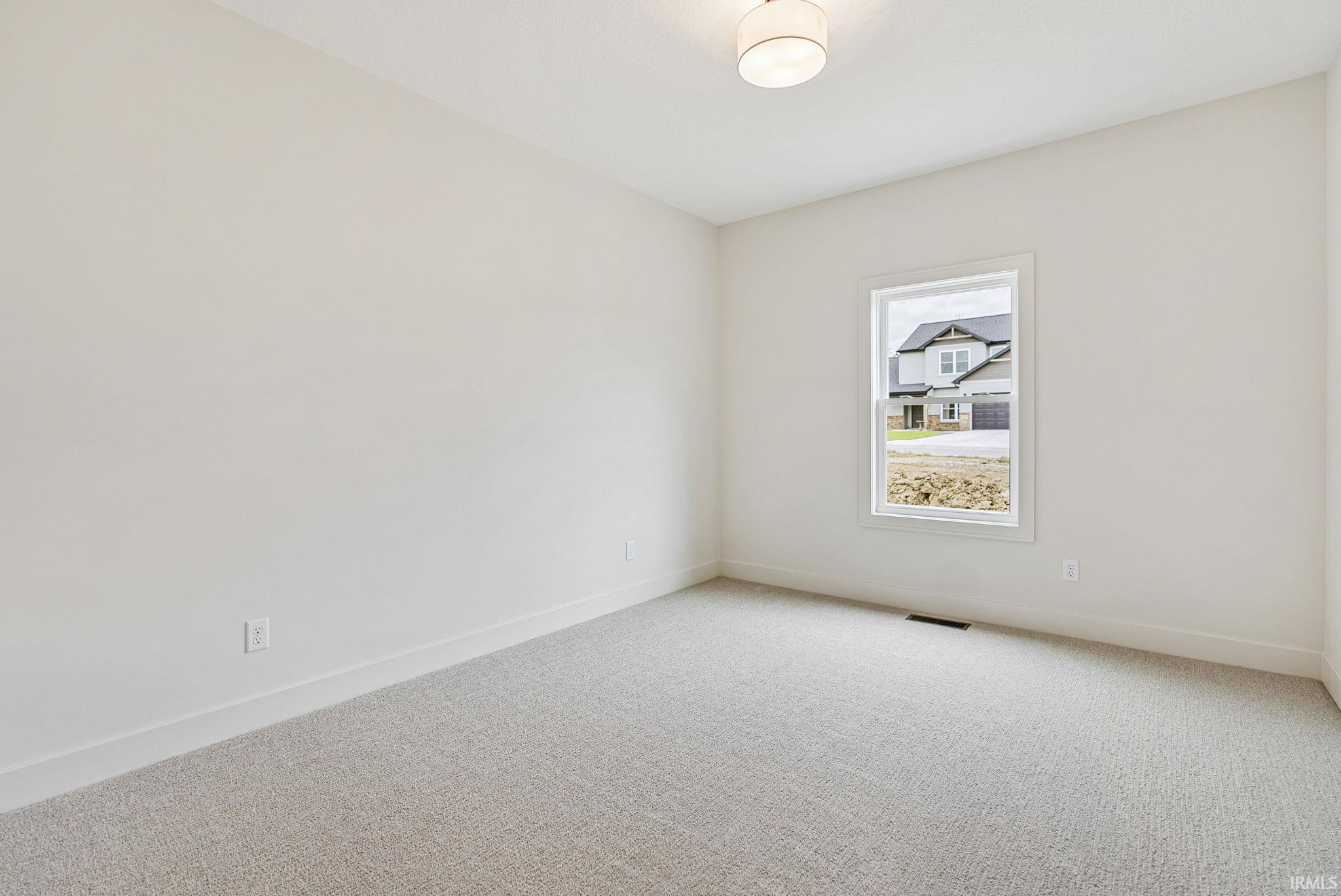 Carpeted interior room featuring neutral wall paint, white trim, a single window, and a flush-mount ceiling light fixture
