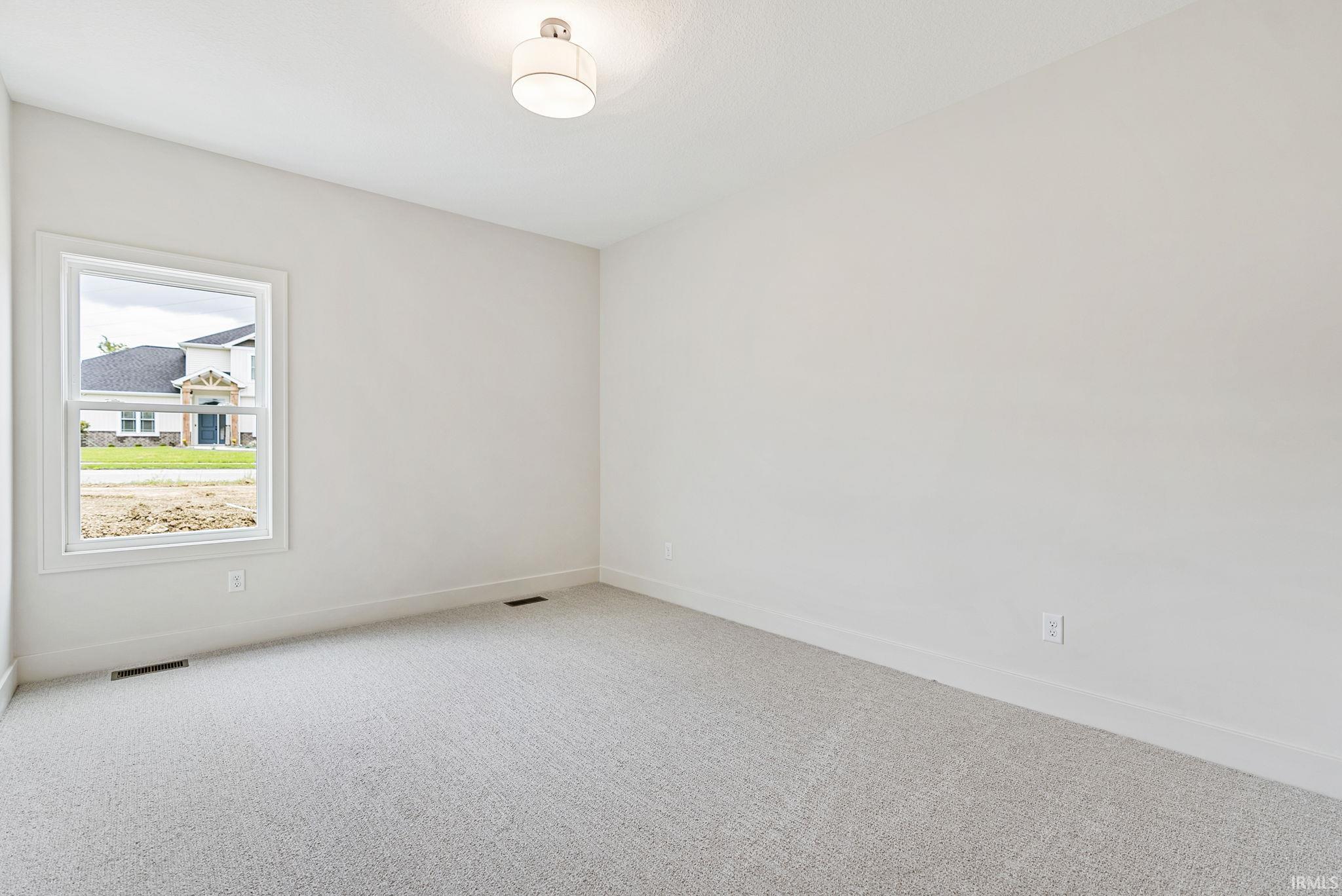 Neutral wall paint, light-colored carpet flooring, and a single window with white trim