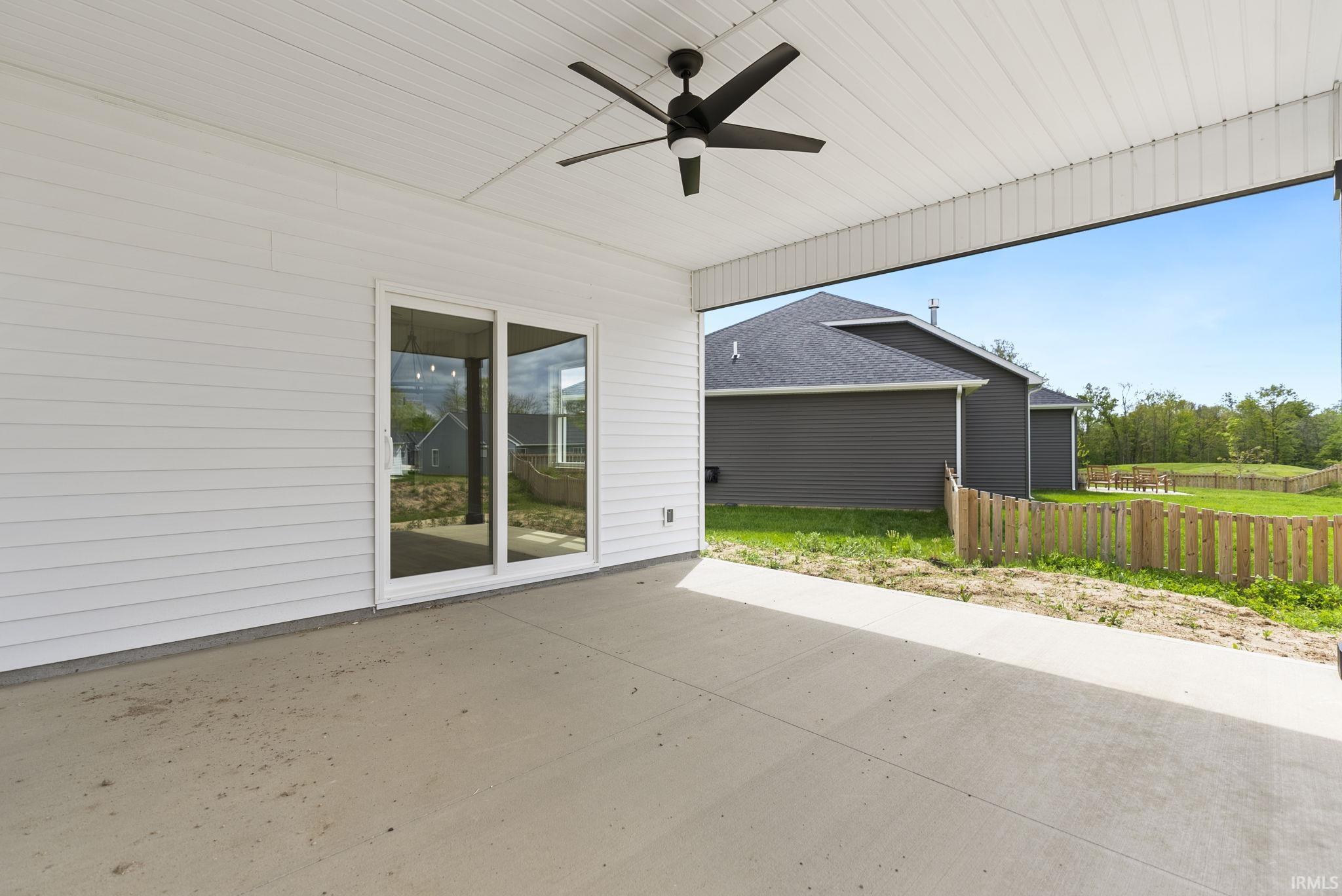 Spacious covered patio with a ceiling fan, white siding, and a sliding glass door