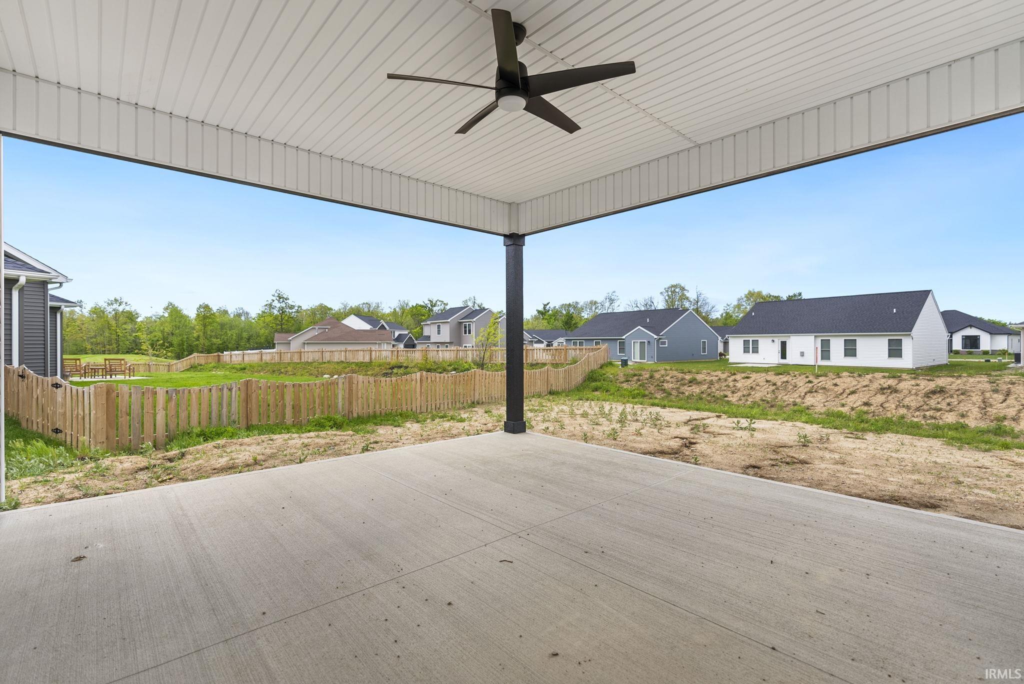 Expansive covered patio with a ceiling fan, concrete flooring, and a black support column
